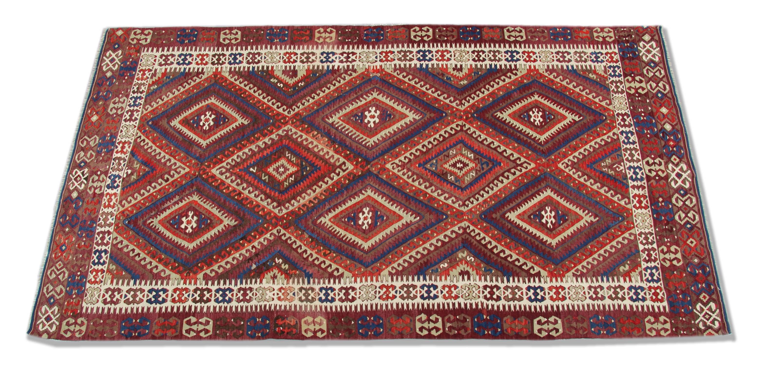 This red rug is a Turkish carpet rug has woven by very skilled weavers in Turkey, who used the highest quality wool and cotton. The flat-weave rug has dark & light red, ivory, blue, white, cream and dark brown colours. The red and blue background of