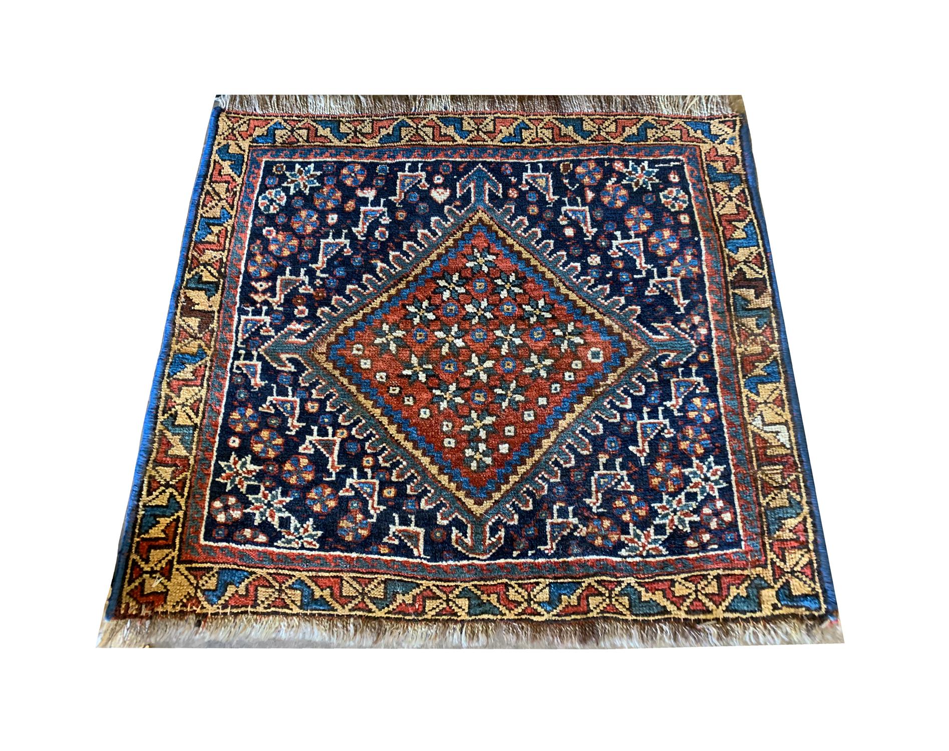 This small antique Caucasian wool rug was woven by hand in Azerbaijan in the 1880s with the finest locally sourced materials. The central design features a large square medallion decorated with a floral design in green and ivory on a rich red