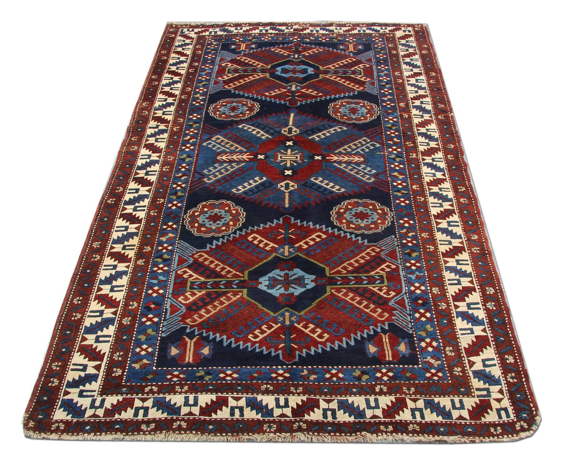 An excellent handwoven Kazak rug example of Caucasian handmade carpet rug weaving from the Kazak region. Though this dark blue rug has a shiny background and 3 stylish central medallion patterned rugs may seem like from a distance, but this woven