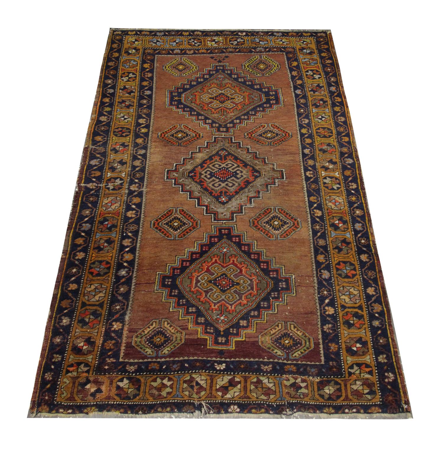 This fine wool rug is a great example of oriental rugs woven in the early 20th century. The central design features a bold medallion pattern woven in deep blue, orange and beige on a brown/beige background. A repeating motif pattern border has then