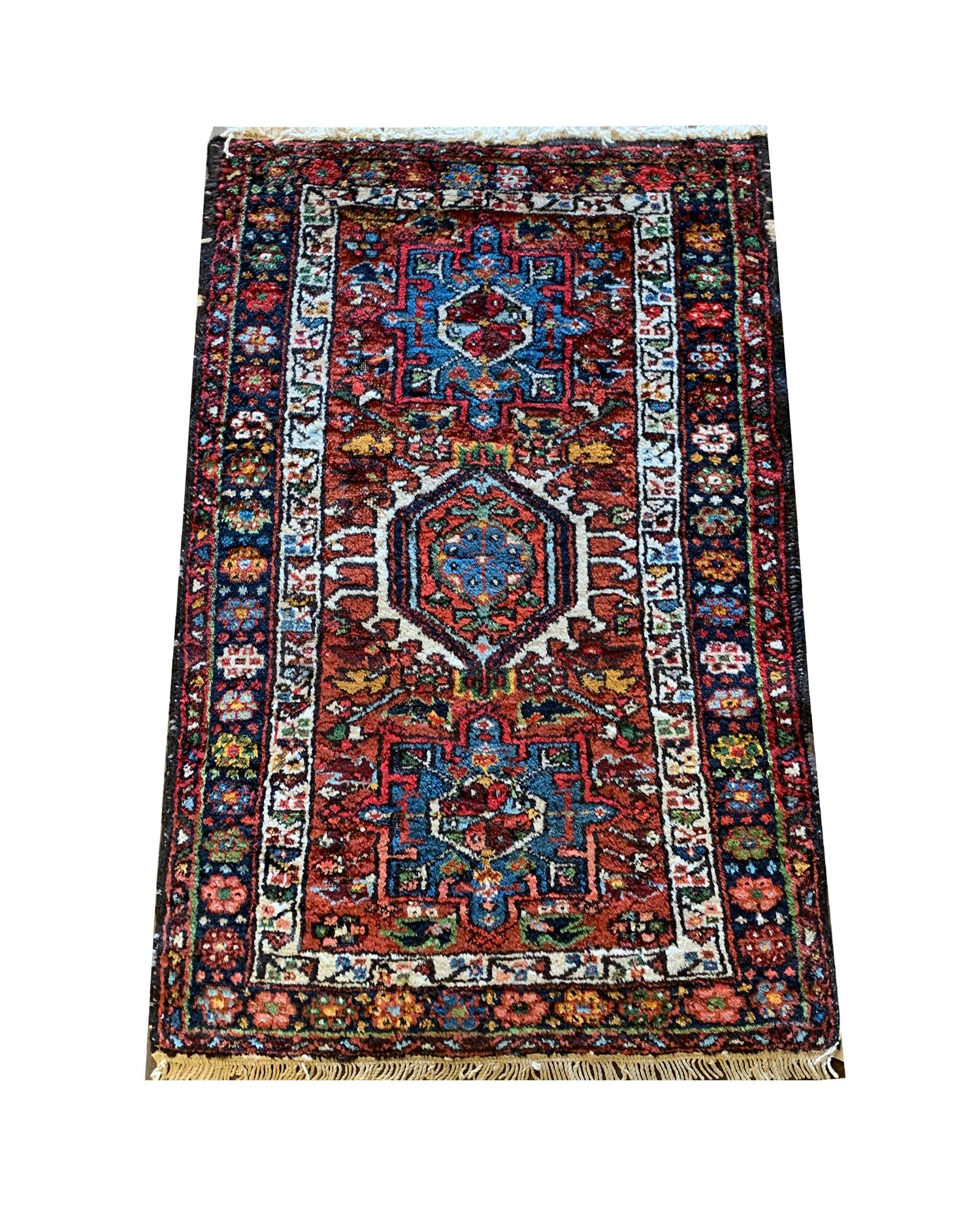 This unique small handwoven Caucasian wool rug has been constructed with three highly-decorative tribal medallions on a rich red-brown background with accents of cream, blue, yellow and green. Both the color and design of this piece make it the