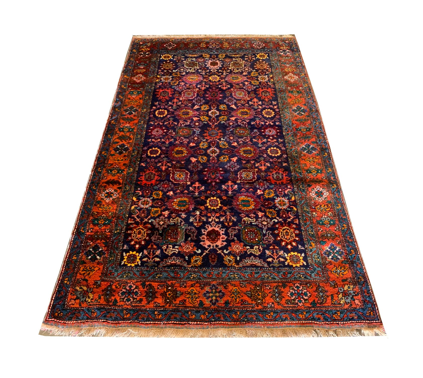 This elegant wool rug was woven by hand in the 1920s in the Caucasus region. The central design has been woven on a deep blue background with contrasting accents of orange, red, yellow and pink that make up the highly decorative floral design. This