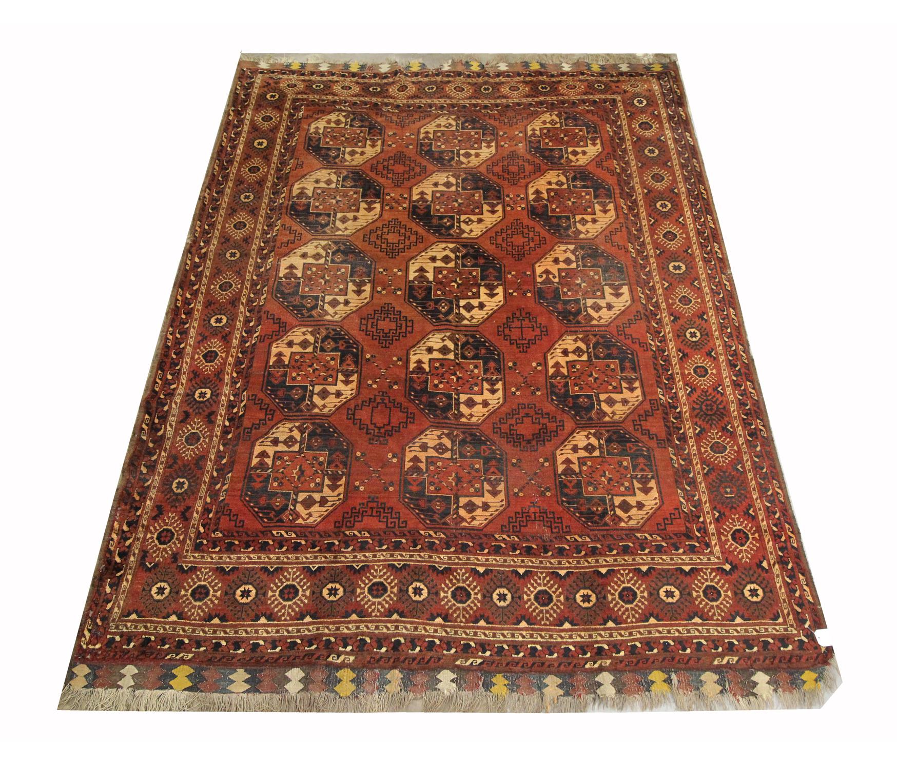 This file wool rug is an antique Turkmen carpet woven by Ersari Turkmens in the 1920s. The central design features a traditional medallion design woven on a rust background in cream and broad blue accents. The Tribal design seen here is traditional