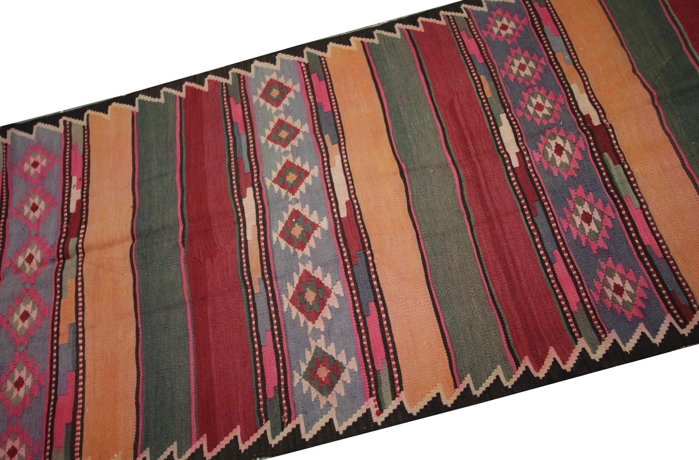 This kilim rug was woven by hand in the 1960s/70s with a simple stripe design and intertwined with purple, orange and brown, green accents in a repeating pattern. The colour palette and design make it easily matchable to both classic and