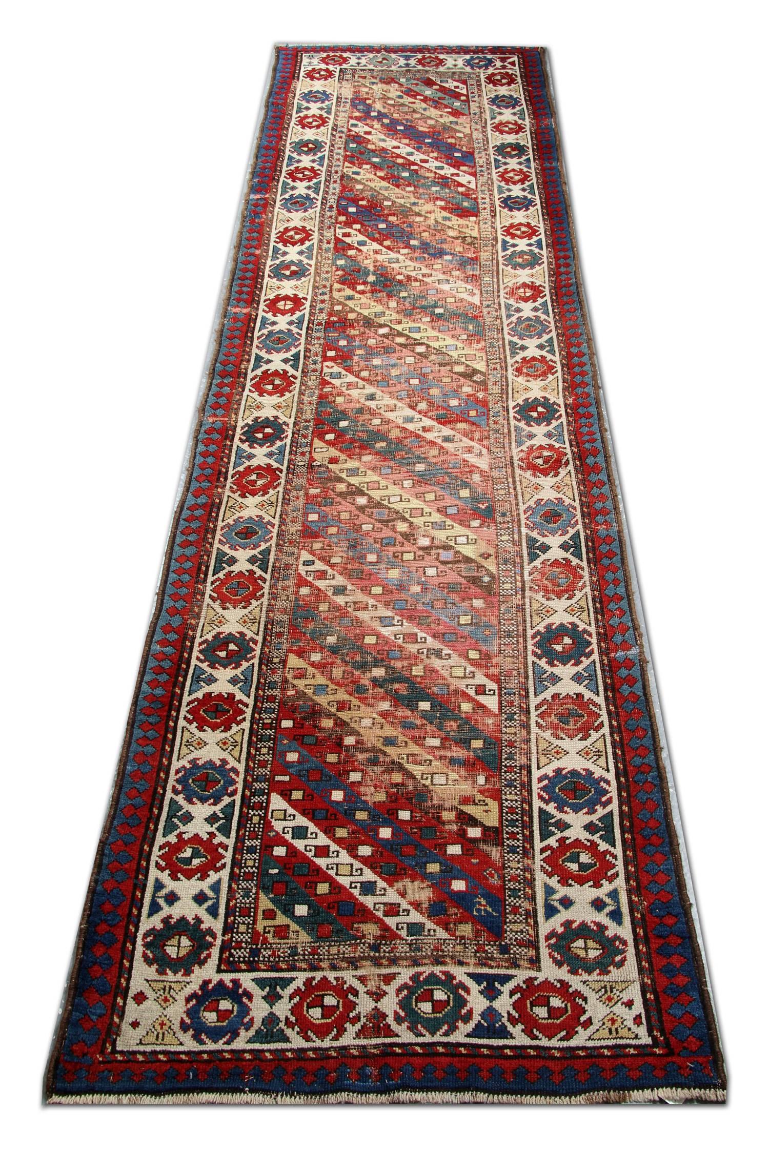 Tapis oriental fait main, né des traditions nomades, ce tapis rayé antique de Ganjeh présente un spectaculaire ensemble de rayures modulaires et de motifs de bordures classiques qui ont un style graphique linéaire de grands tapis. Le champ chaud et