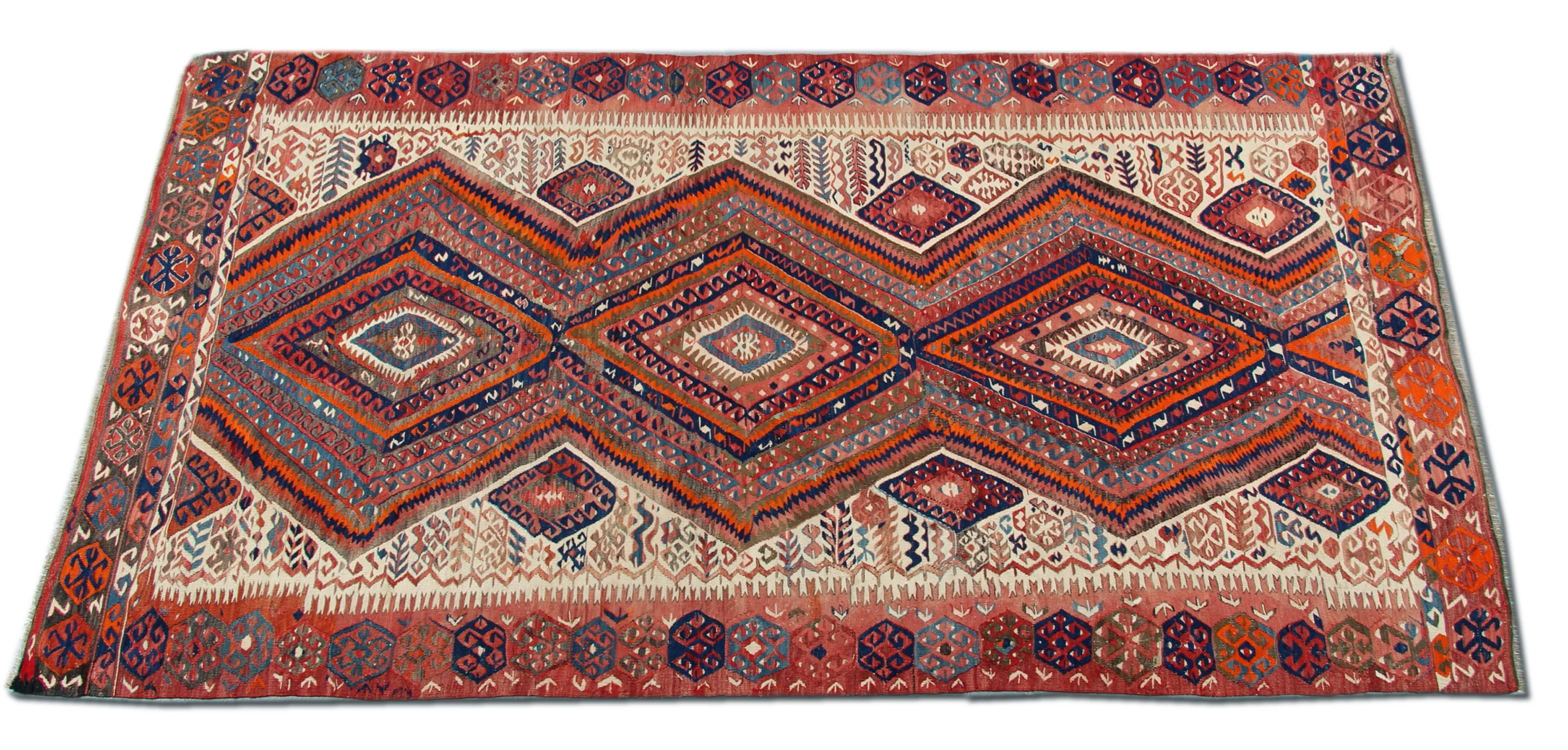 Esta alfombra oriental Kilim antigua es una alfombra turca hecha a mano por tejedores muy hábiles de Turquía, Anatolia, que utilizaron lana y algodón de la mejor calidad. La alfombra de tejido plano tiene colores rojo claro, naranja, verde grisáceo,