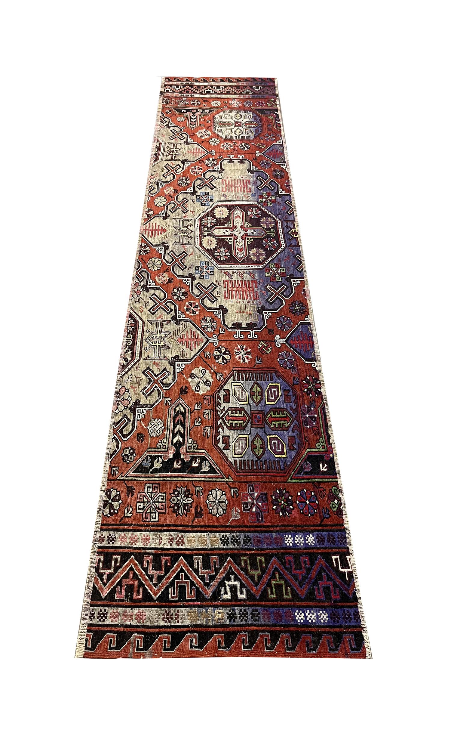 This truly unique soumak runner rug is a fantastic example of antique textiles woven in 1910. The design features bold geometric pattens intricately woven in accents of deep red, beige, blue and brown. Easily stle this fine wool area rug with both