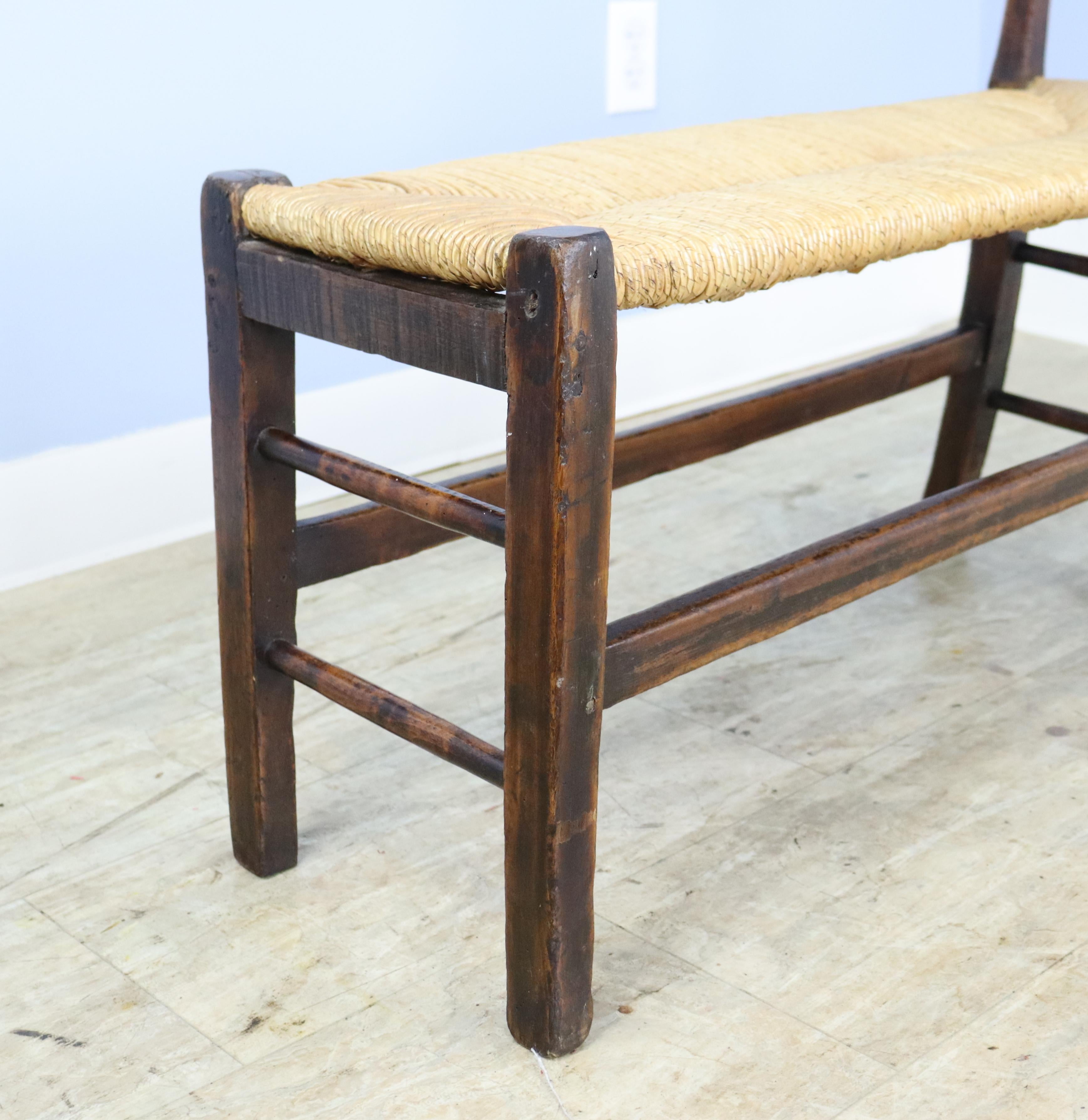 A charming early rush seated stool with all of its original seat materials and a single arm. The piece is solid and sturdy. the back legs have a slight flare which may be intentional but we cannot say for sure.