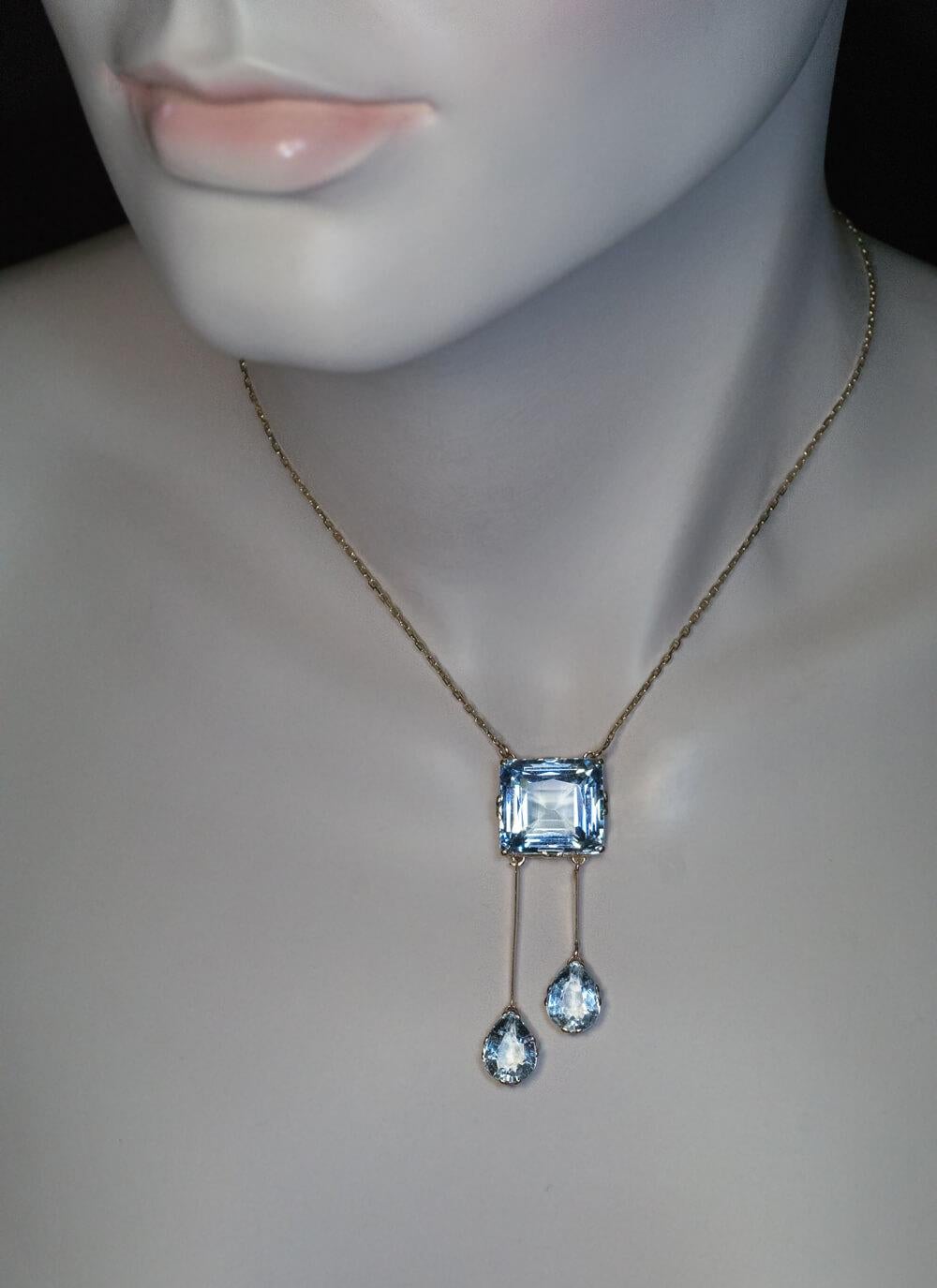 Made in Saint Petersburg between 1908 and 1917.

The 14K gold necklace features a 21.89 ct rectangular mixed cut aquamarine of an excellent saturated greenish blue color, accented by two sparkling drop shaped smaller aquamarines.

Total length of