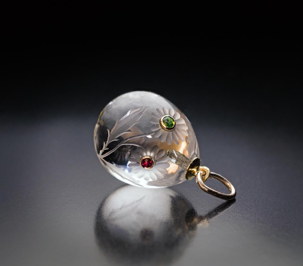 Made in St. Petersburg in the 1890s.

This superb gold mounted rock crystal egg pendant is engraved with an Art Nouveau flower, the two flower heads of which are embellished with a green demantoid and a red spinel set in a gold bezel.

The