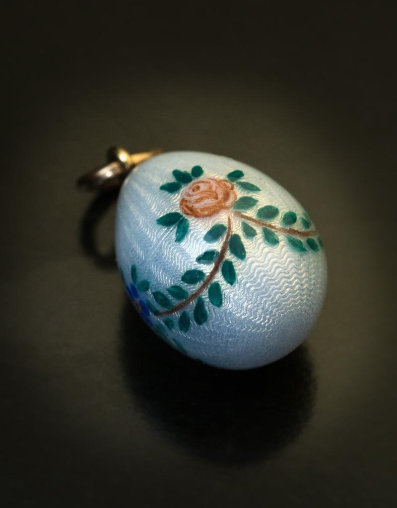 Made in St. Petersburg between 1899 and 1908.

This antique Russian gold mounted miniature egg pendant is covered with a delicate silver blue guilloche enamel and painted with a rose and forget-me-not garland.

Marked with maker’s initials ‘AW’ and