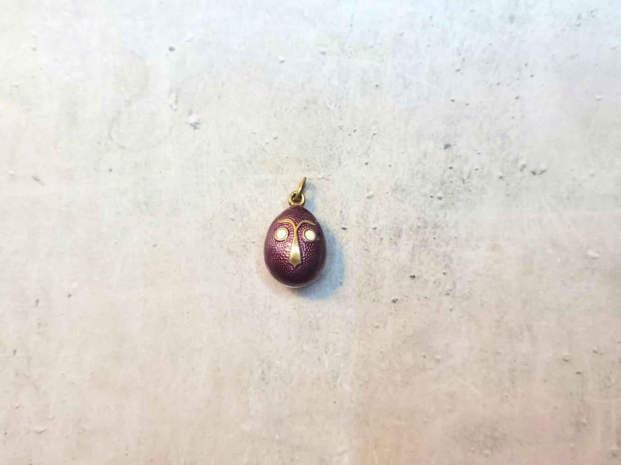 Voici un superbe pendentif conçu en forme d'œuf impérial russe en argent doré et émail avec un visage de bande dessinée sur les deux faces. Le corps de l'œuf est émaillé d'un magnifique émail guilloché violet. L'utilisation de différents matériaux