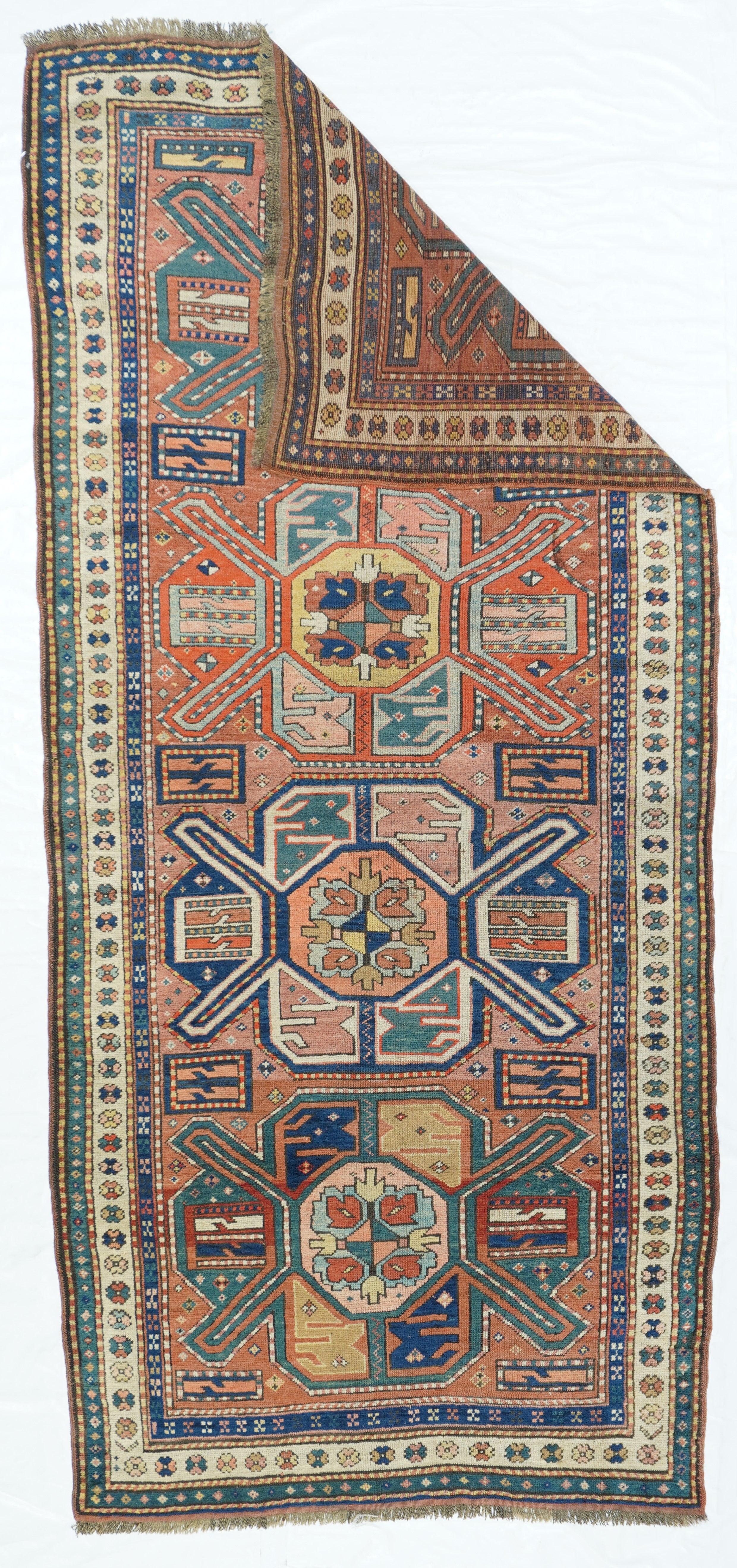 Antique Russian Kazak rug,measures : 3'11'' x 8'7''. The well-abrashed light rust to dusty rose field of this southern Caucasian kellegi display four large Turkmen-style vígulsvì with ivory, royal blue, green and khaki details Each motif is centred