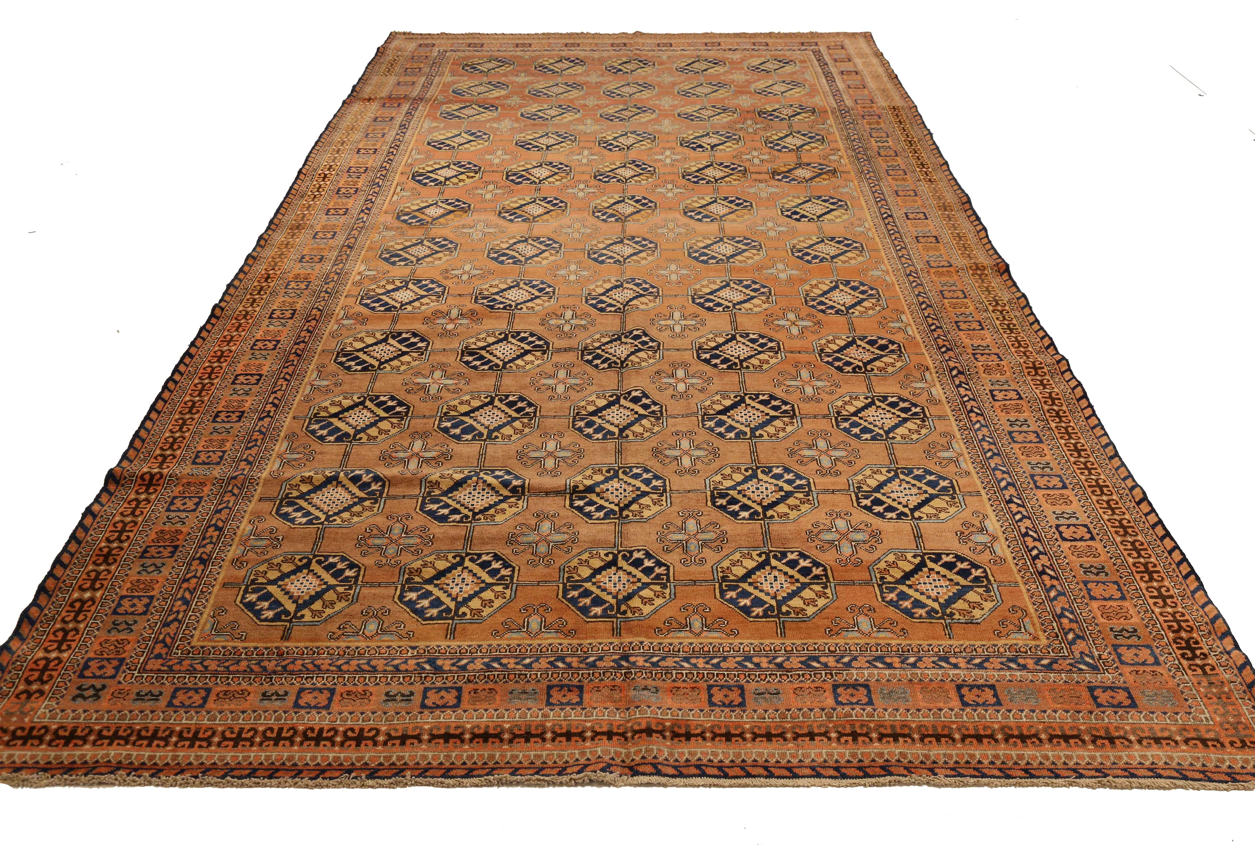 Antique Russian rug handwoven from the finest sheep’s wool and colored with all-natural vegetable dyes that are safe for humans and pets. It’s woven using Khotan design featuring rows of octagon shaped medallions in navy and beige over orange field.
