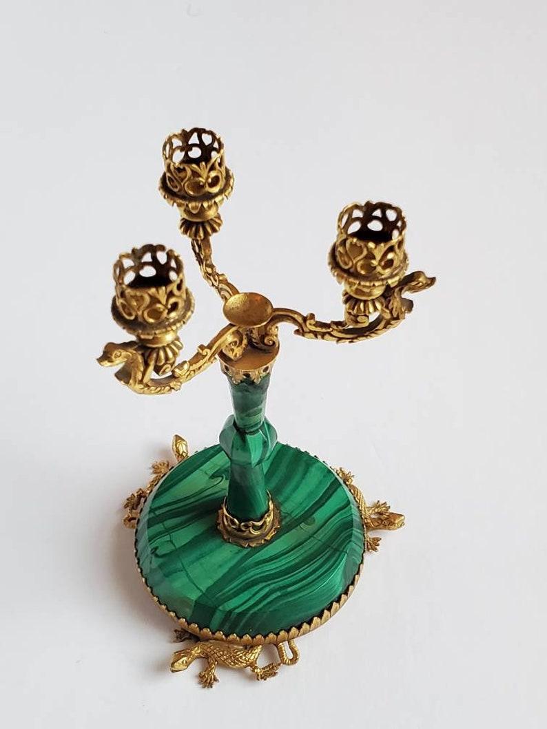 Un candélabre miniature de qualité en malachite et bronze doré orné de bronze doré du tournant de la fin du 19ème - début du 20ème siècle. Cette étonnante antiquité rare, faite à la main, aux détails exquis, présente trois bras à volutes qui se