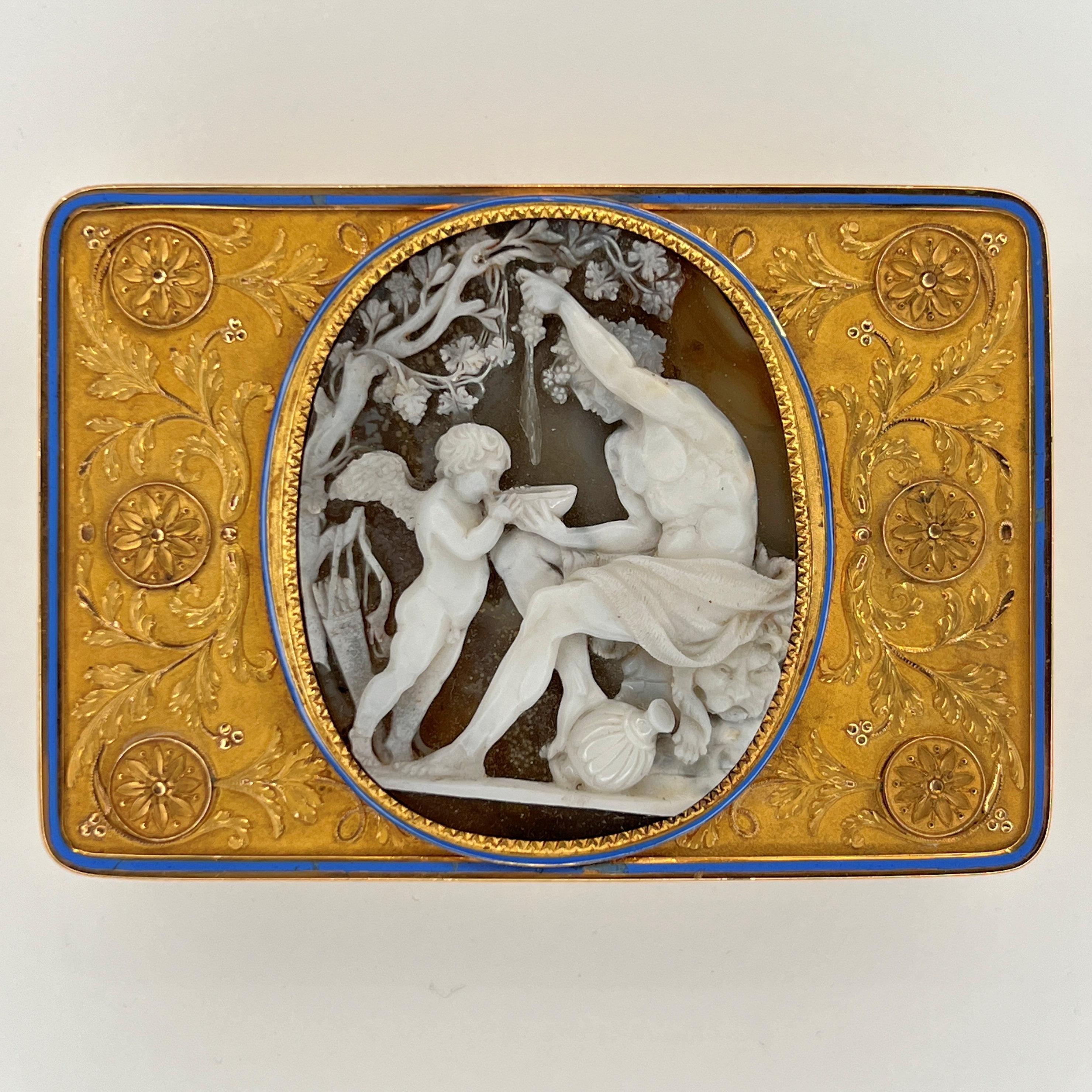Our wonderful snuff box features a finely carved agate relief depicting Bacchus and Cupid, scrolling foliate motifs and roundels against a matte ground, and cover with blue enamel border.  Interior with the stamped marks for St. Petersburg, the