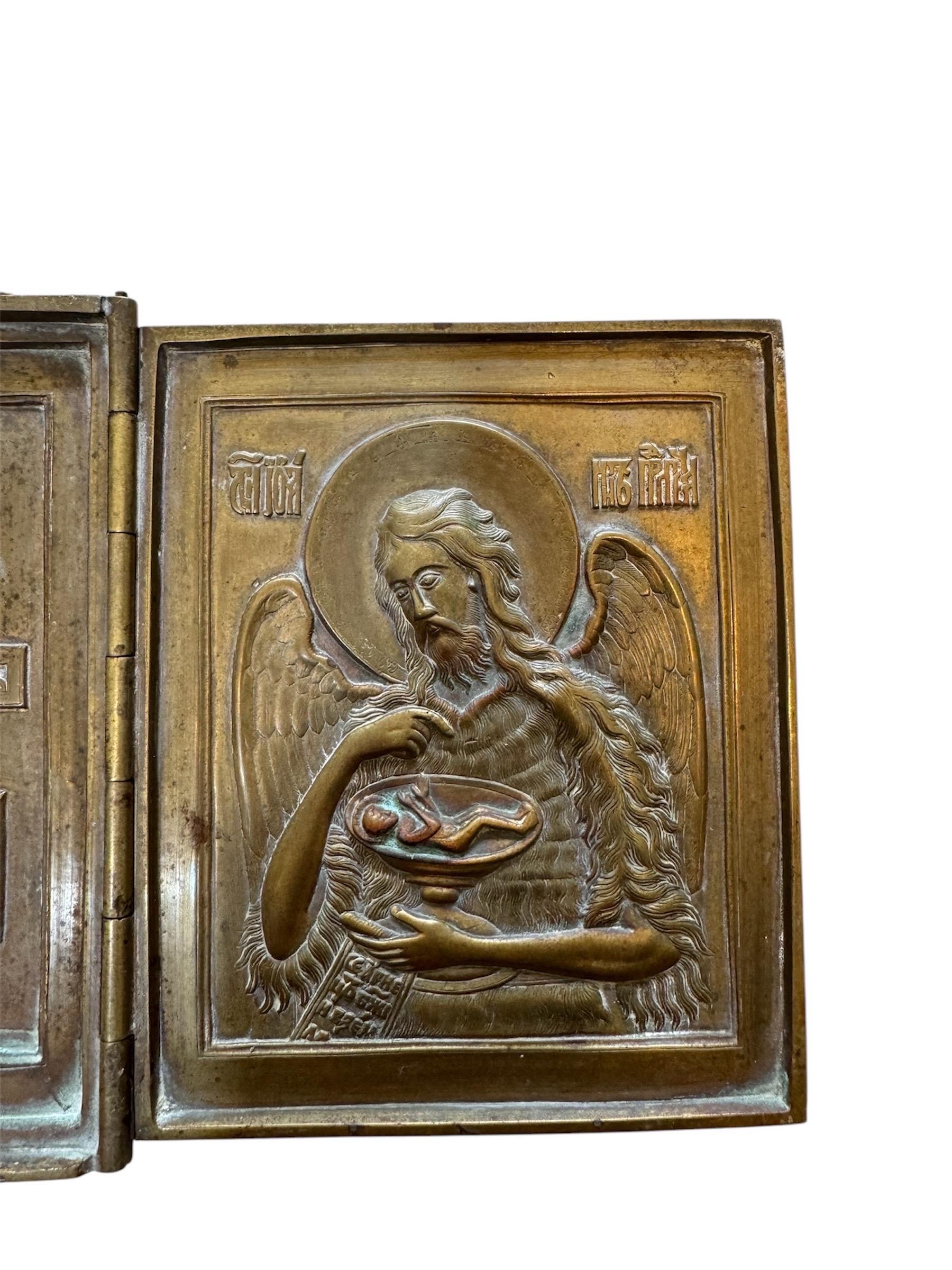 Il s'agit d'une ancienne icône triptyque orthodoxe russe en laiton, un artefact religieux pliable couramment utilisé pour la dévotion personnelle et les voyages. Le panneau central représente le Christ Pantocrator, avec un geste de bénédiction et un