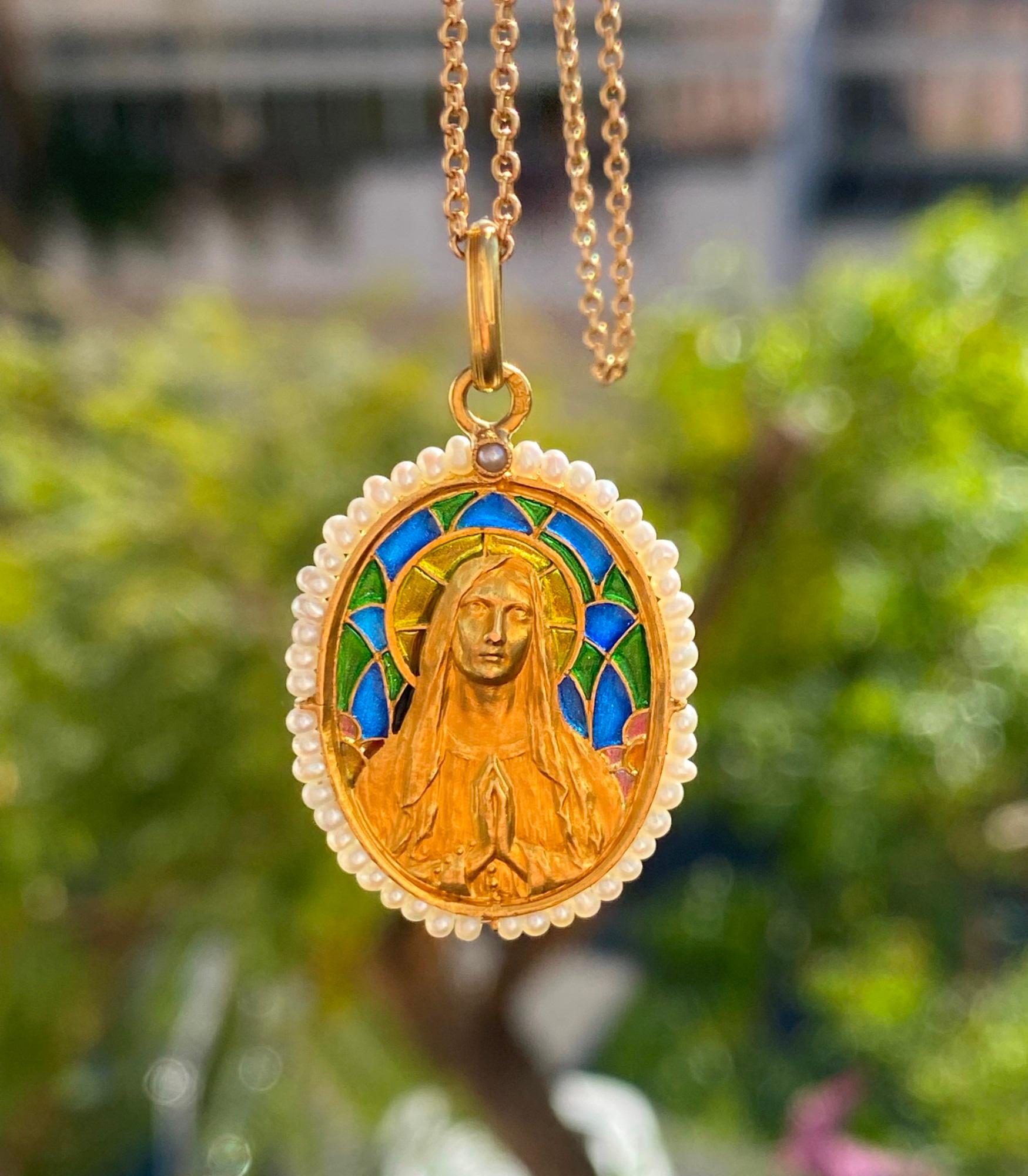 This is a beautiful antique religious pendant of the Virgin Mary in detailed high relief gold.  The pendant has 4 colors of plique a jour blue, green, orange and gold. There is a halo of seed pearls around the pendant.  There is a Russian gold
