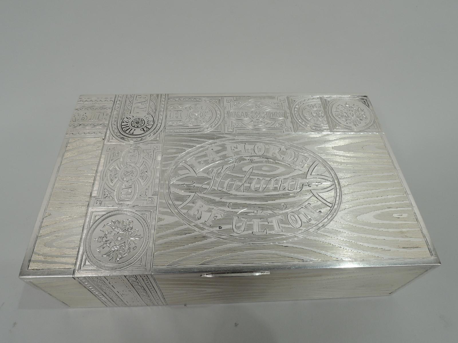 Russian 875 silver novelty cigar box. Rectangular with straight sides; cover flat and hinged. Gilt interior with interlaced script monogram. Trompe l’oeil wood panels with realistic grain and tax stamps. Based on the packaging for La Flor de Habana