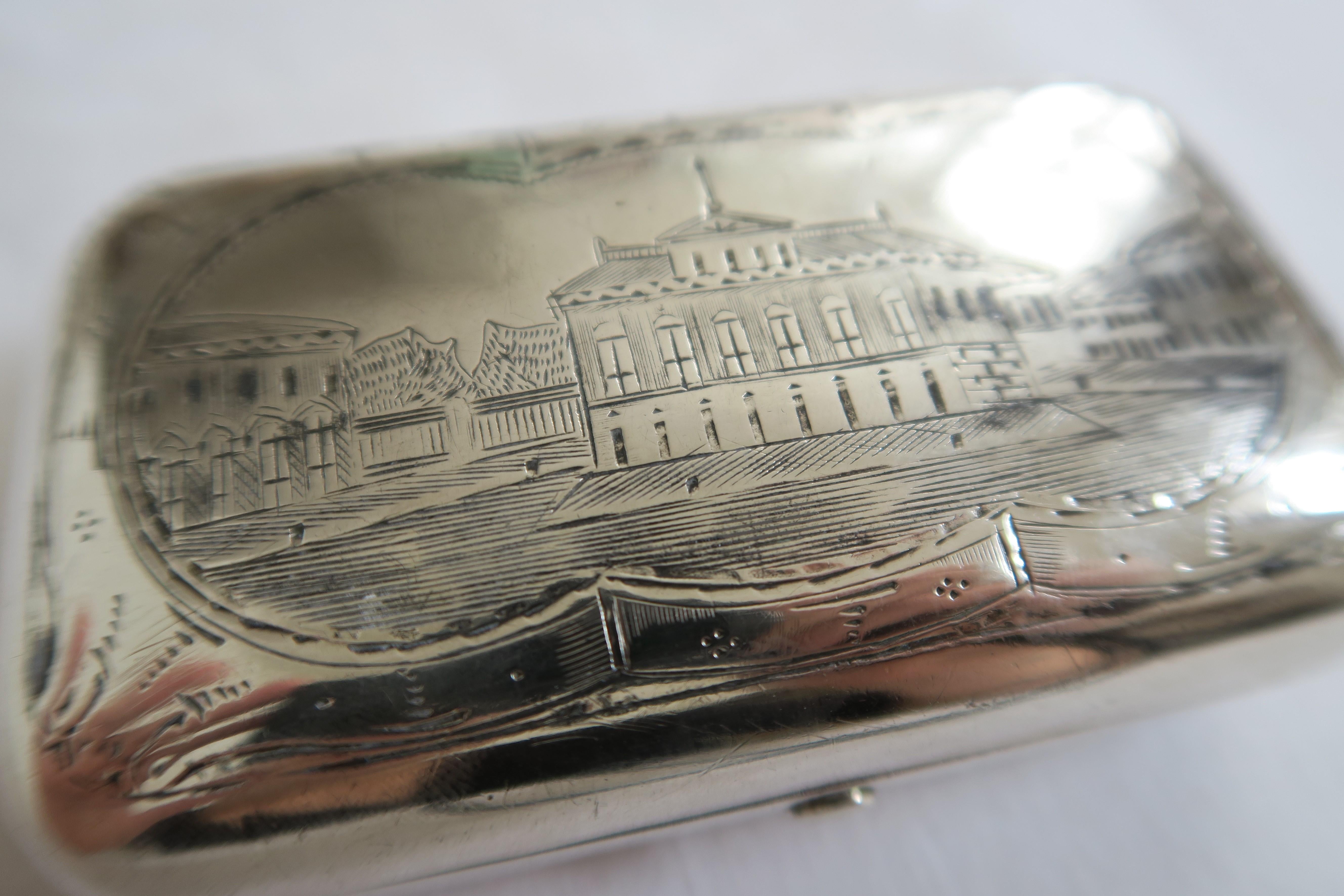 The item for sale is a Tular silver snuffbox. It has an oval shape and the lid is engraved with a Moscow landmark building in an ornamental frame. The backside is engraved with chess board pattern and a generously ornamented crest carrying the
