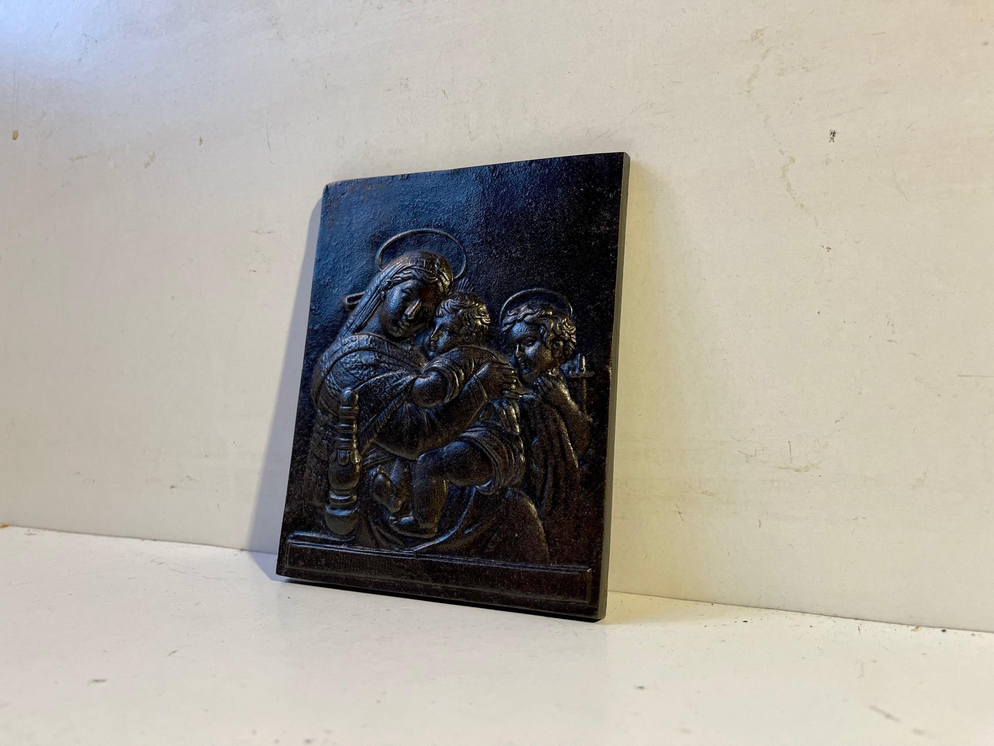 Small yet heavy wall relief - Russian icon in cast bronze. It depicts a seated Virgin Mary holding a very young Jesus and an Angel holding a crucifix. It was made in Russia circa 1870-90. It has no markings. Measurements: 13 x 10 x 0.5 cm.
