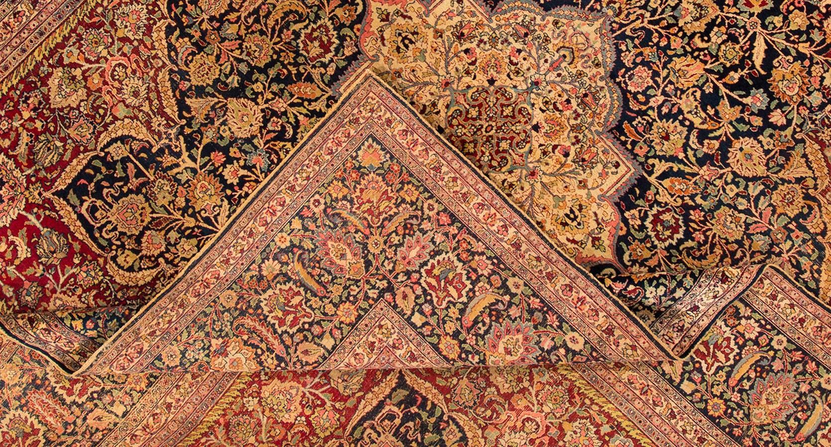 Antique 1920s distress Persian Mashed carpet. This piece features a wide, dark blue border with intricate floral detailing, a rust/red field with similar all-over patterning, and a small central medallion. Measures: 11.03 x 13.09.