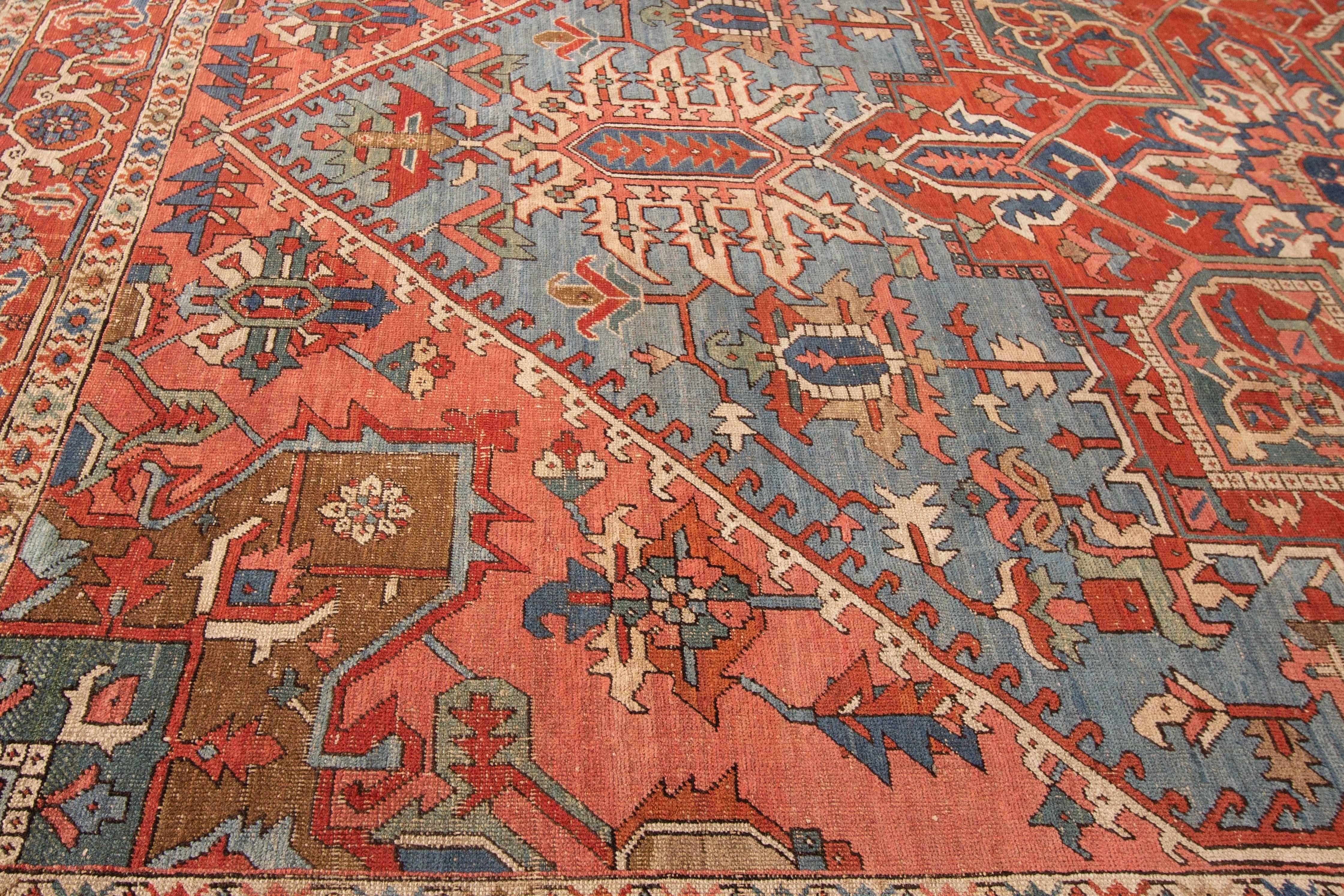 Hand-knotted, 1905 antique Persian Heriz rug. This piece has a floral medallion design in teal and earth tones on a rust/red field. Measures 9.08x12.09.