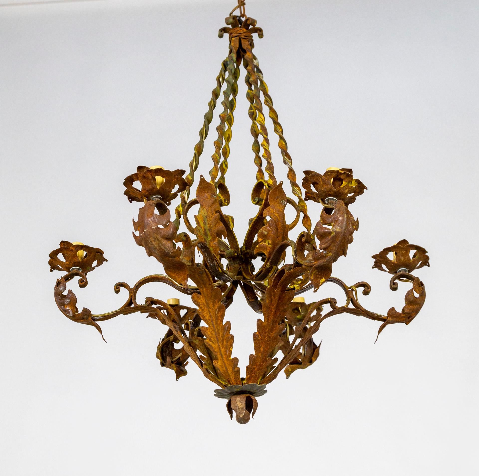A 6-light chandelier with a diamond-shaped structure comprised of four twisted metal stems, C-curves, and curling leaves. The metal has a unique patina of rust and touches of yellow ochre and olive green paint. Newly wired. Chain length variable.
