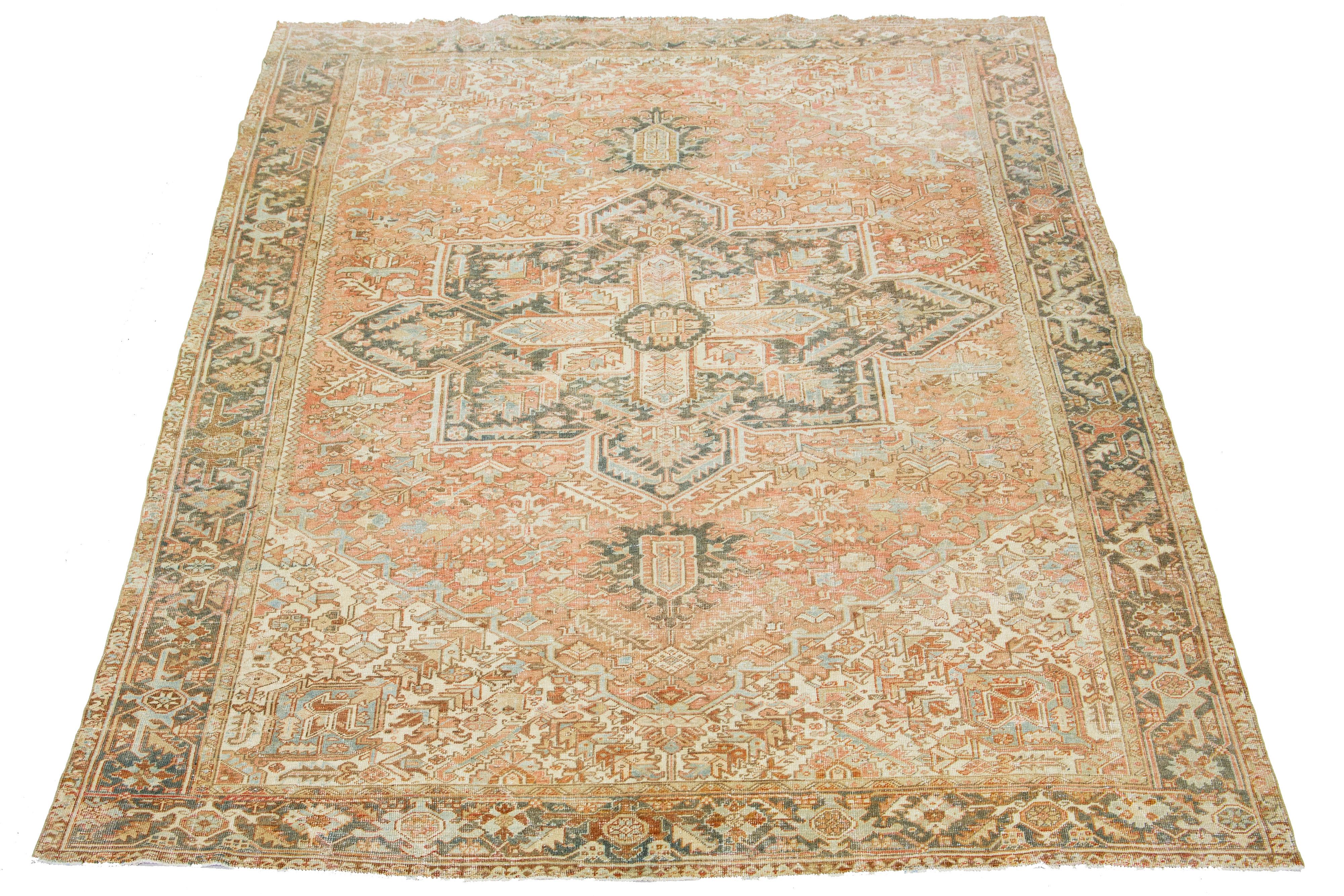 This antique Persian Heriz rug is crafted with hand-knotted wool. The rust-colored field features a captivating medallion pattern embellished with shades of blue, beige, and gray.

This rug measures 9'7