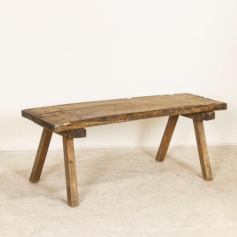 The thick slab top draws one to this rustic console table due to the heavy distress seen in every scratch, crack and gouge that came from years of constant use( likely in a butcher's shop). Areas of extreme wear and even dried up old wormholes (of