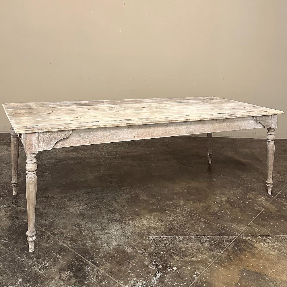 Antique Rustic Country French Whitewashed Dining Table was hand-crafted to last for generations, and features a solid plank top, reinforced corners over single plank aprons, and finely turned legs for a touch of refinement over more rustic designs. 