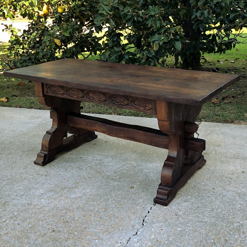 Antique rustic Dutch Gothic library table is a marvel of rural craftsmanship! Created from old-growth oak, it was designed to last for centuries, with a thick plank top resting on two massive, thick side supports that are connected with a carved