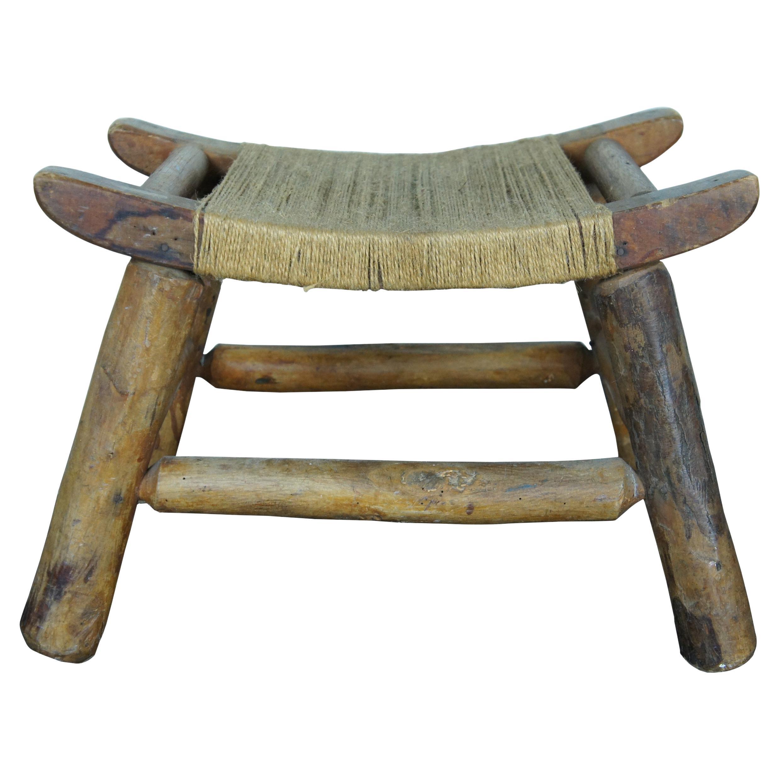Tabouret de traite / repose-pieds rustique du début du 20e siècle / country farmhouse / style Shakers, avec des pieds sculptés en forme de rondins d'Adirondack, un plateau arqué et un siège simple en corde de jute.

Dimensions :
18