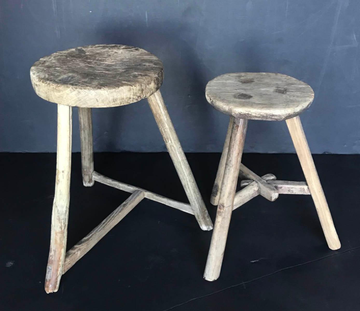 Antique, rustic elm wood stools with mortise and tenon construction. Great weathered patina on both. Stool on the left has a T stretcher and measures 17 x 18 x 19.5 H, the seat is 12 inches in diameter. The right stool has a Y stretcher and measures