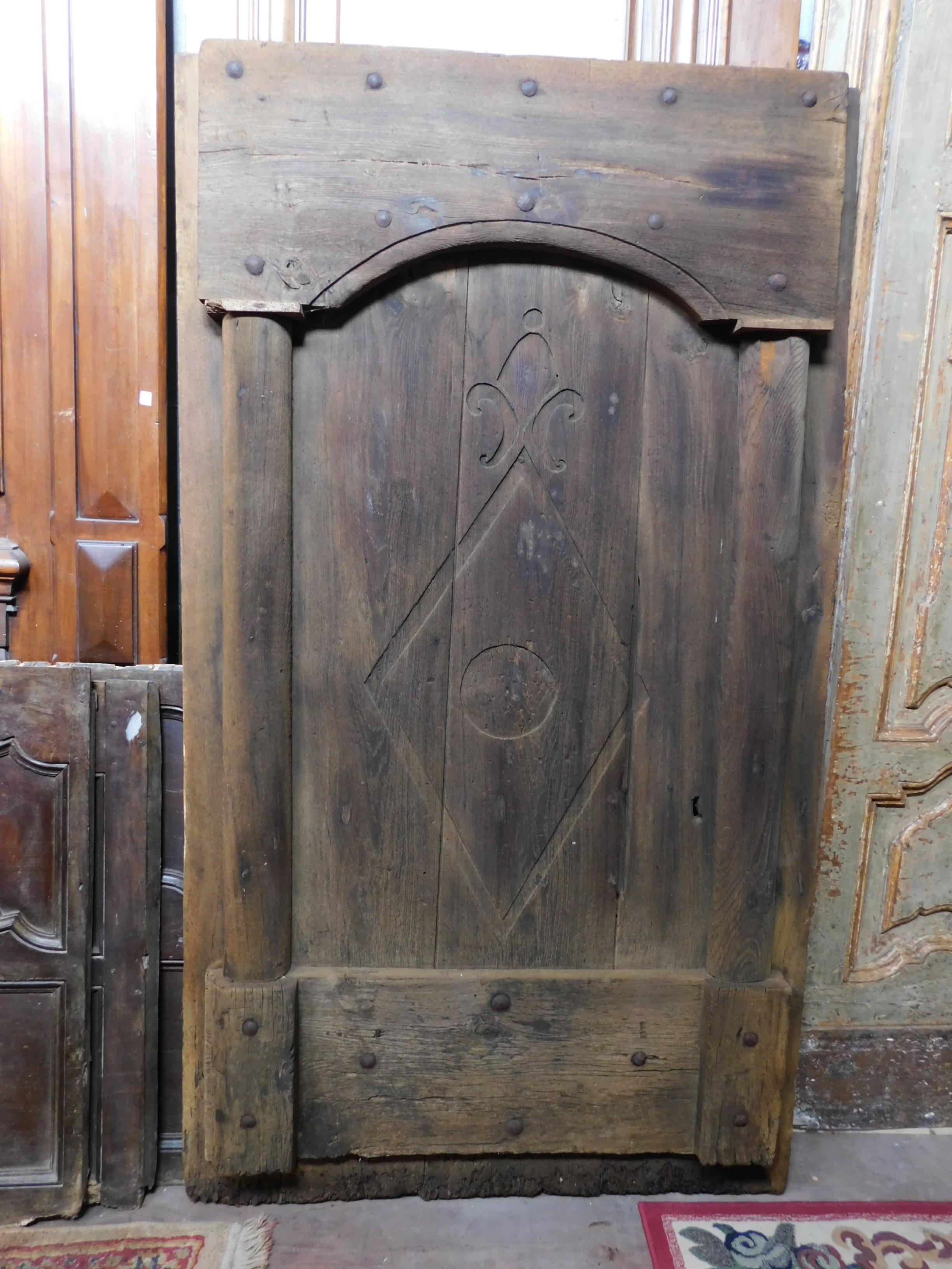 Ancient rustic entrance door, made with dark chestnut wood slabs, hand carved with columns and mountain symbols, made in the 19th century in northern Italy.
Typically rustic of the Italian mountain valleys, fantastic in a cabin or a rustic room,