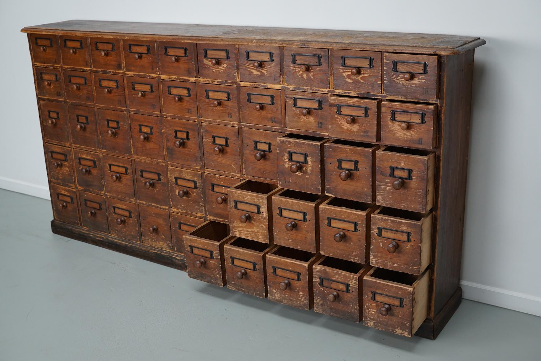 This apothecary bank of drawers was designed and made circa 1910/1920. It was made from pine and it features 50 drawers with wooden knobs. The interior dimensions of the drawers are: DWH 24 x 15 x 12 + 17 cm.