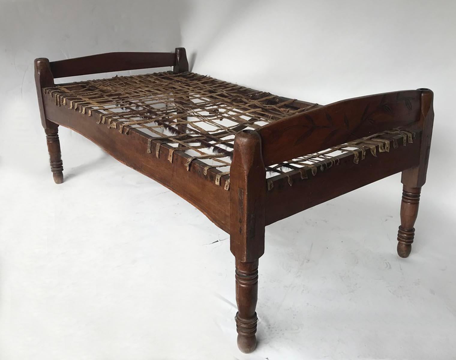 Late 19th to early 20th century cedro (tropical hardwood) bed from Guatemala. Hide straps. Great rustic look. Can be used as a day bed or a bed - just add the mattress! Carving on one side.