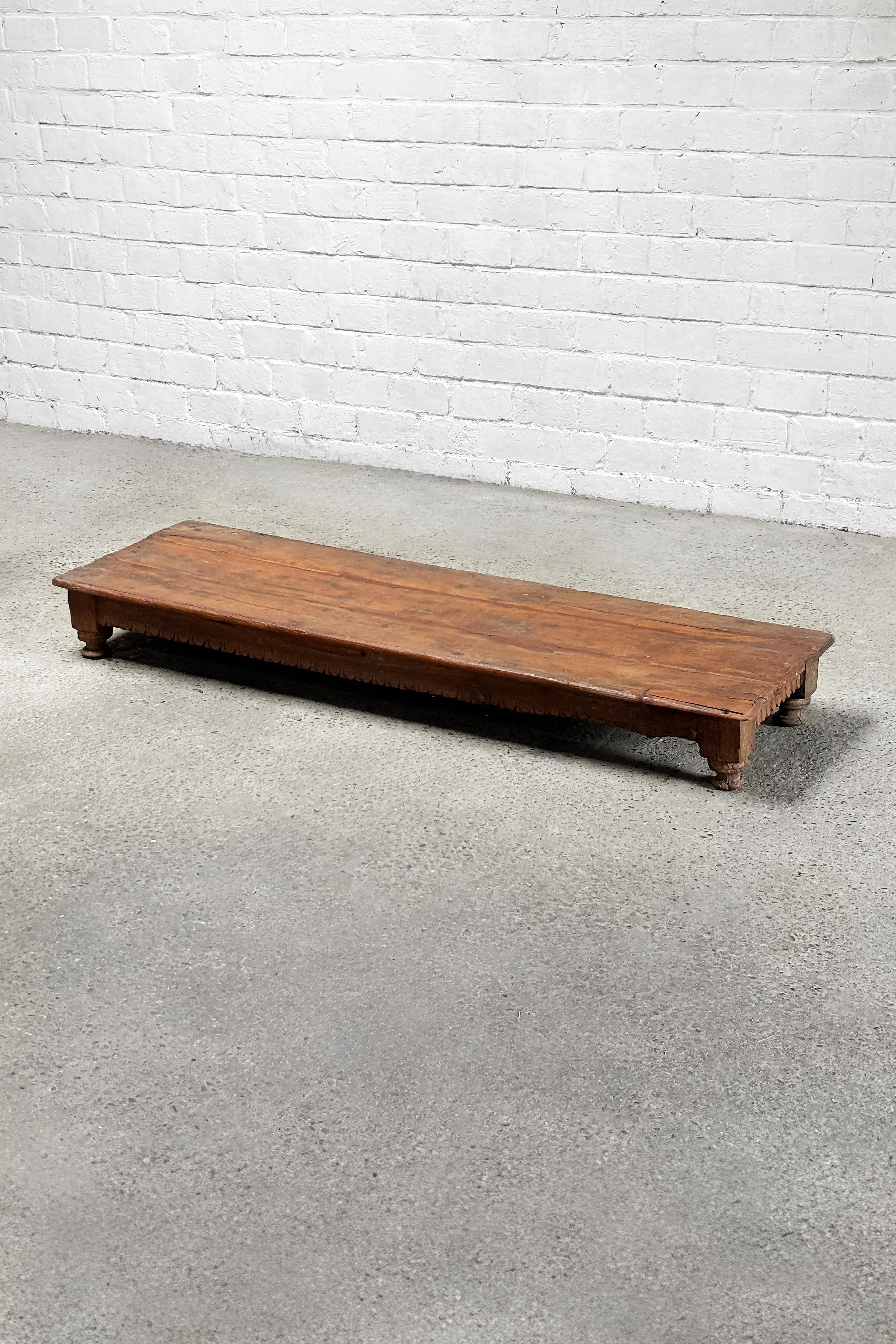 Cette table basse ancienne en bois de l'Inde, datant du début du 20e siècle, présente un charme rustique et un savoir-faire traditionnel. Construit en bois dur massif, il présente un design robuste avec des détails sculptés à la main le long des