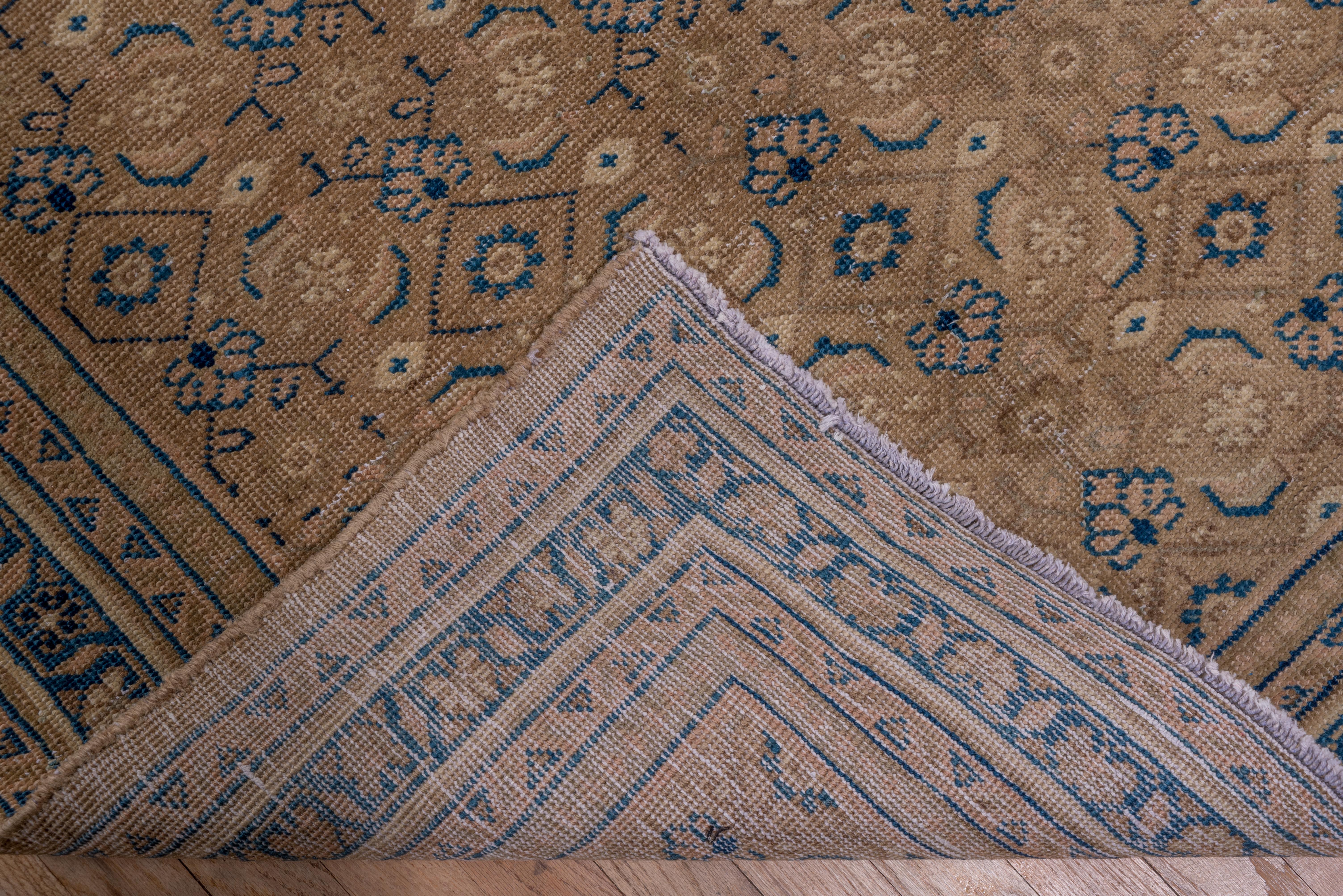 Un simple motif Herati, composé de diamants ouverts et de petites palmettes bleu foncé, recouvre soigneusement le champ brun clair de ce tapis rustique de Perse occidentale, avec une bordure principale bleu foncé de palmettes en éventail. La