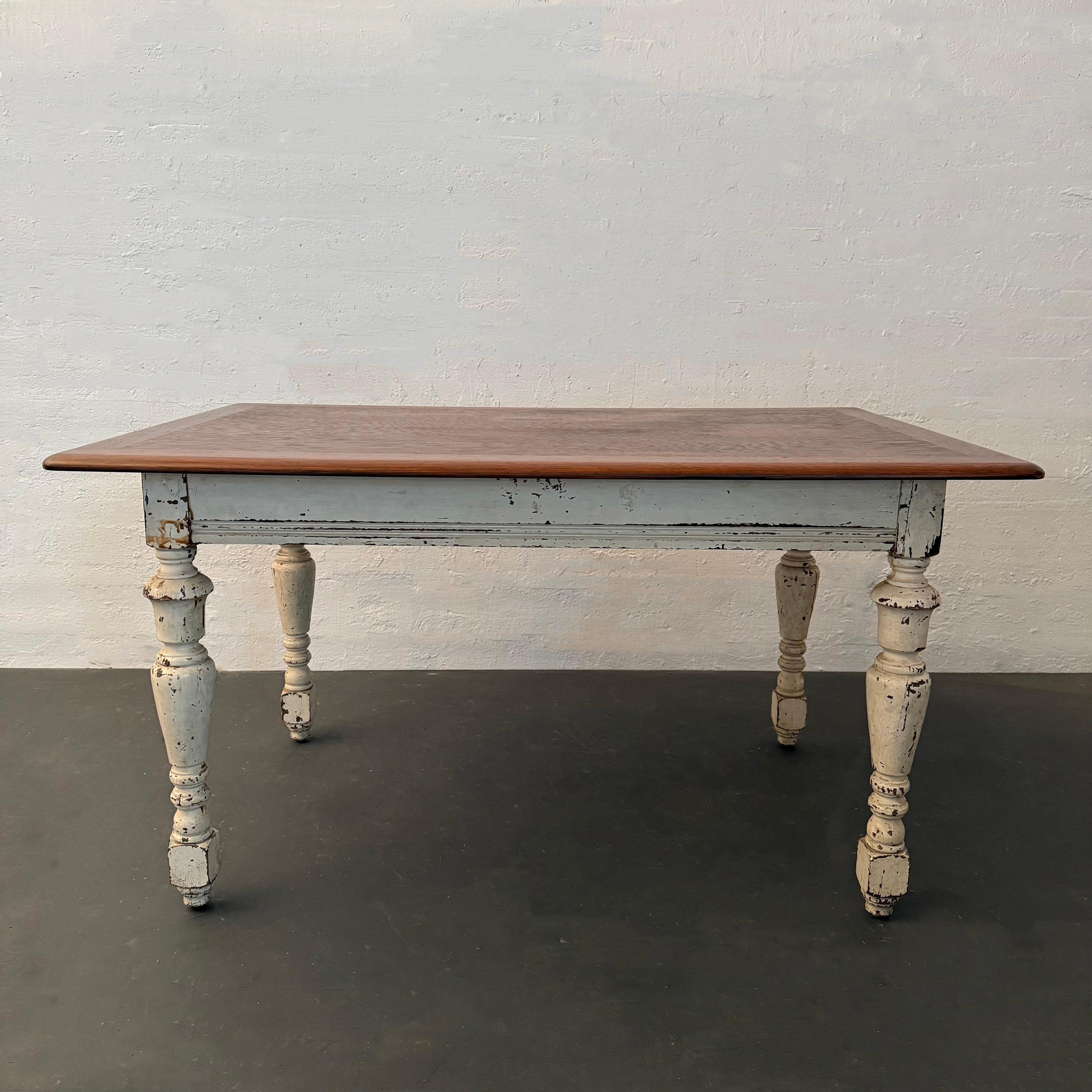 This antique rustic farmhouse table circa 1900 features a natural maple board top, with gently rolled and chamfered edges and stout block shoulders atop turned legs to each corner. The maple shows fine grain interest and rich biscuit hues. The