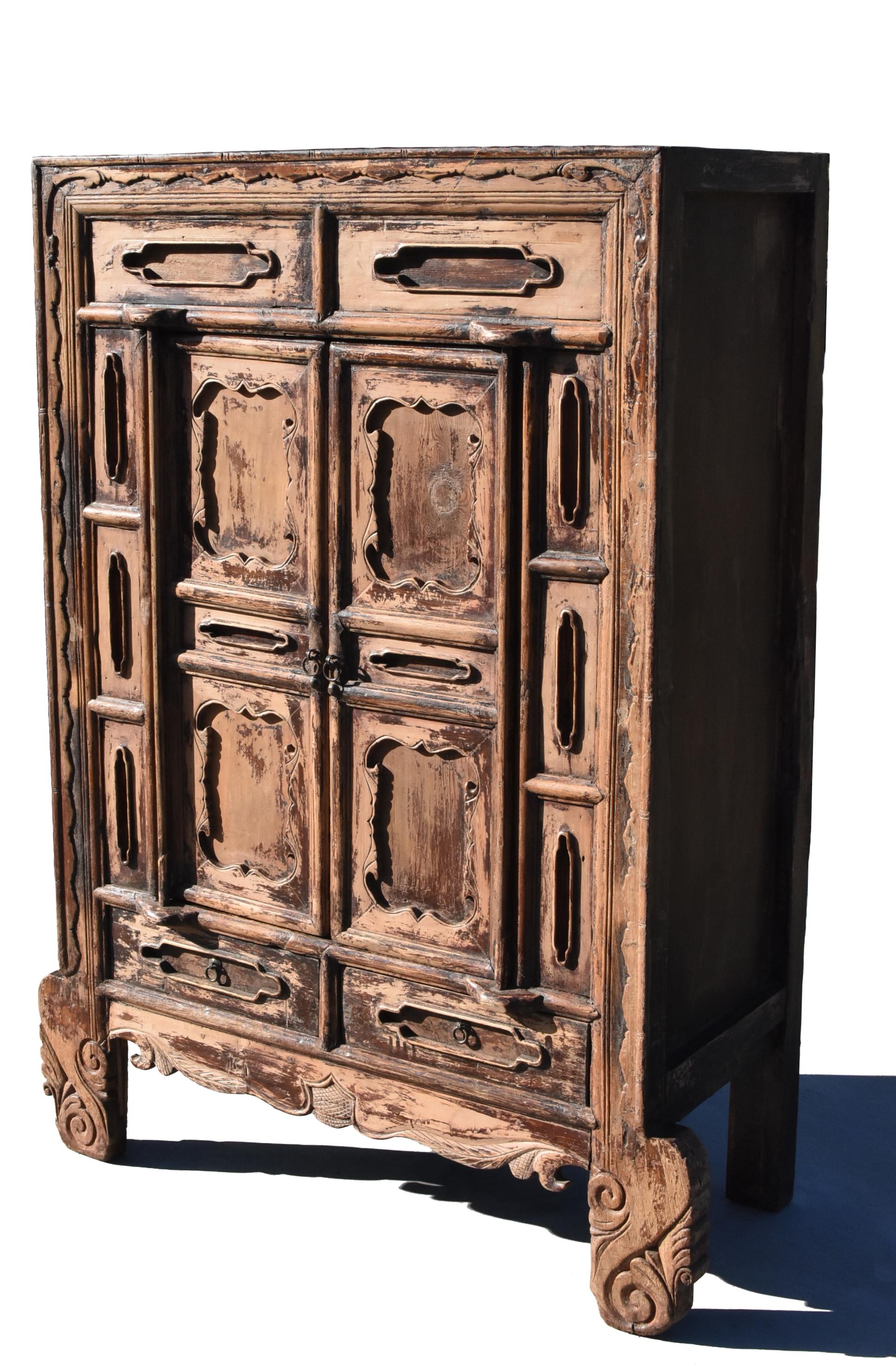 A beautiful 19th century solid wood cabinet from Shan Xi province in northern China. Tenon and mortise construction. Carved open light patterns. Framework depicts the traditional vernacular design of grass scrolls. Dramatic oversize legs flank a