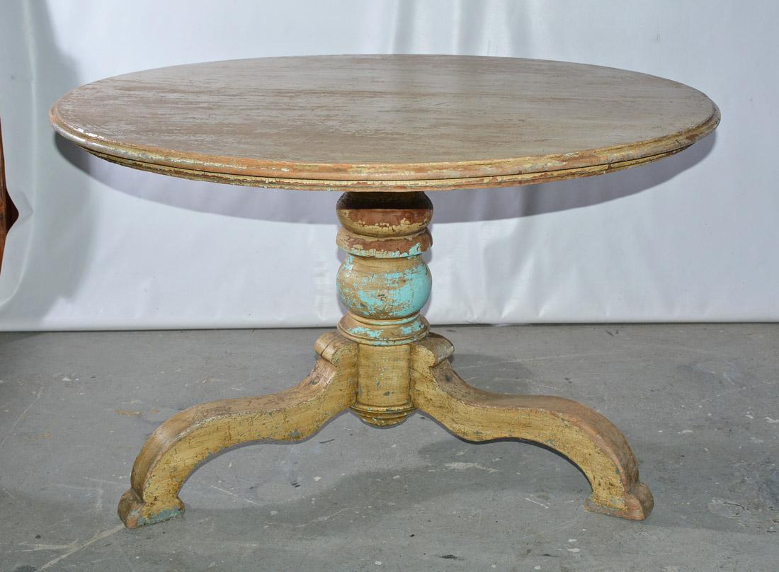 The Victorian rustic country round dining table is made of once painted hard wood. The top has a bevelled edge and is attached to a turned pedestal with three splayed curved legs. Some residue of paint remaining adding to it's charm.