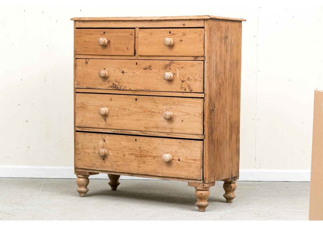 A timeworn and charming Cottage Pine two-over-three Antique Pine chest. Supported on four turned legs, the chest boasts three long drawers, surmounted with a pair of short drawers. All drawers with turned, wooden knob pulls and brass mounts.