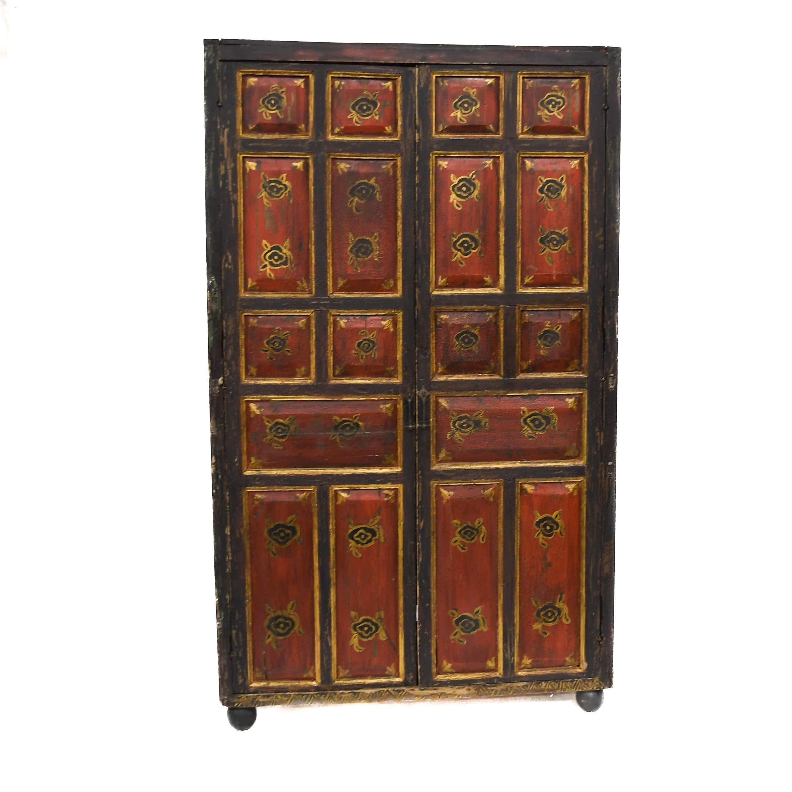 This Antique Rustic Red and Black Cabinet showcases timeworn charm with its distressed red panel doors accented by hand-painted black and gold floral medallions. Framed in black, the design presents a balanced contrast that highlights its geometric