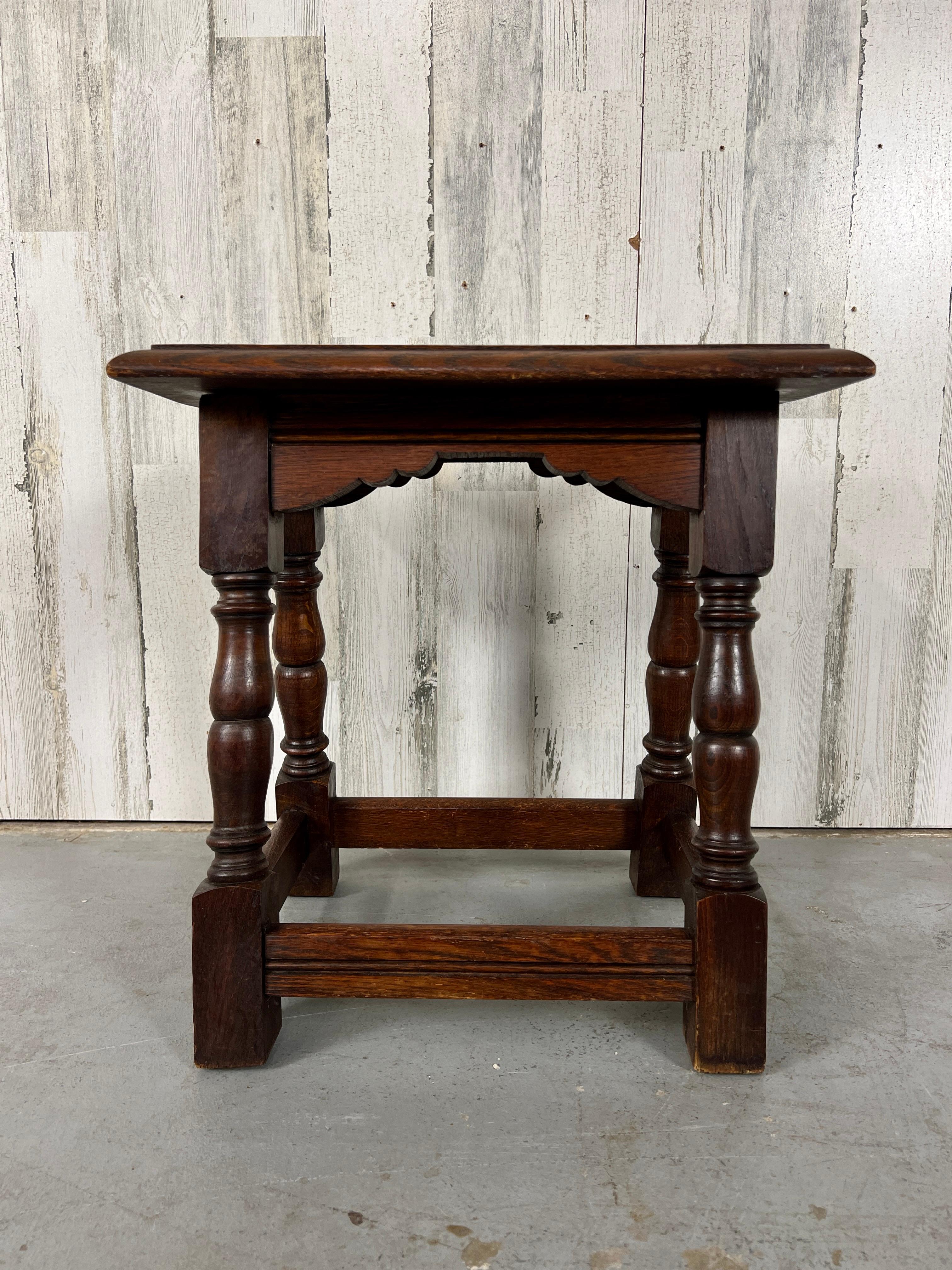 Rustic solid oak European stool with turned legs set on an angular sprawl. This can also be used as a table.