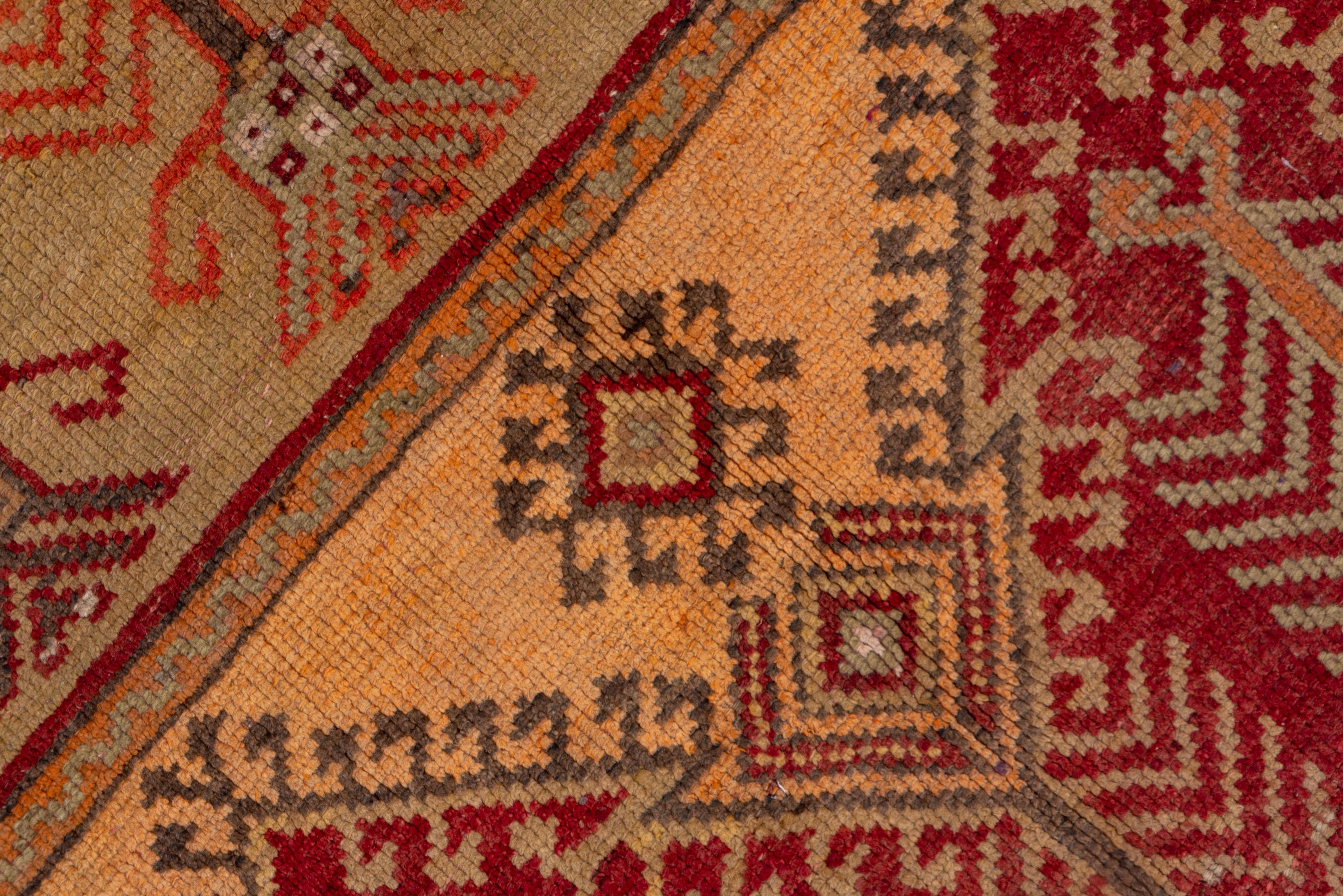 This Anatolian rustic carpet shows five panels, each of two pointed mihrab arches in red or khaki, beneath straw spandrels, and enclosing feathery plants in simple vases. This is a saph (multiple prayer rug) idea. Main border of serrated angled