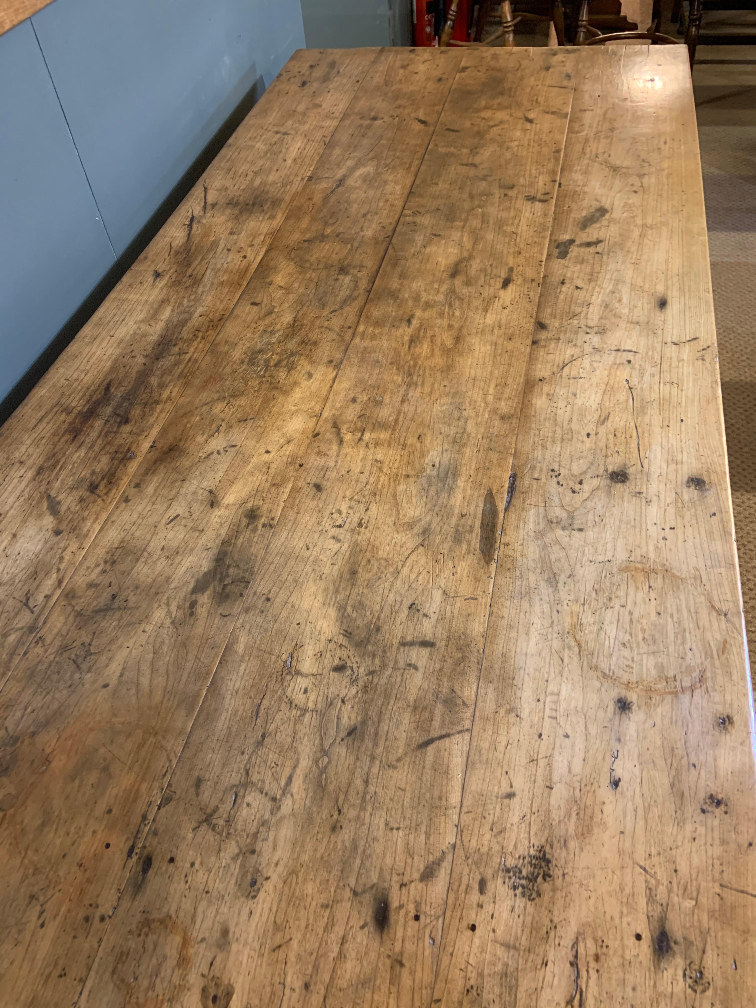 Antique rustic wide pale cherry farmhouse table with a four plank top and tapered legs.
 