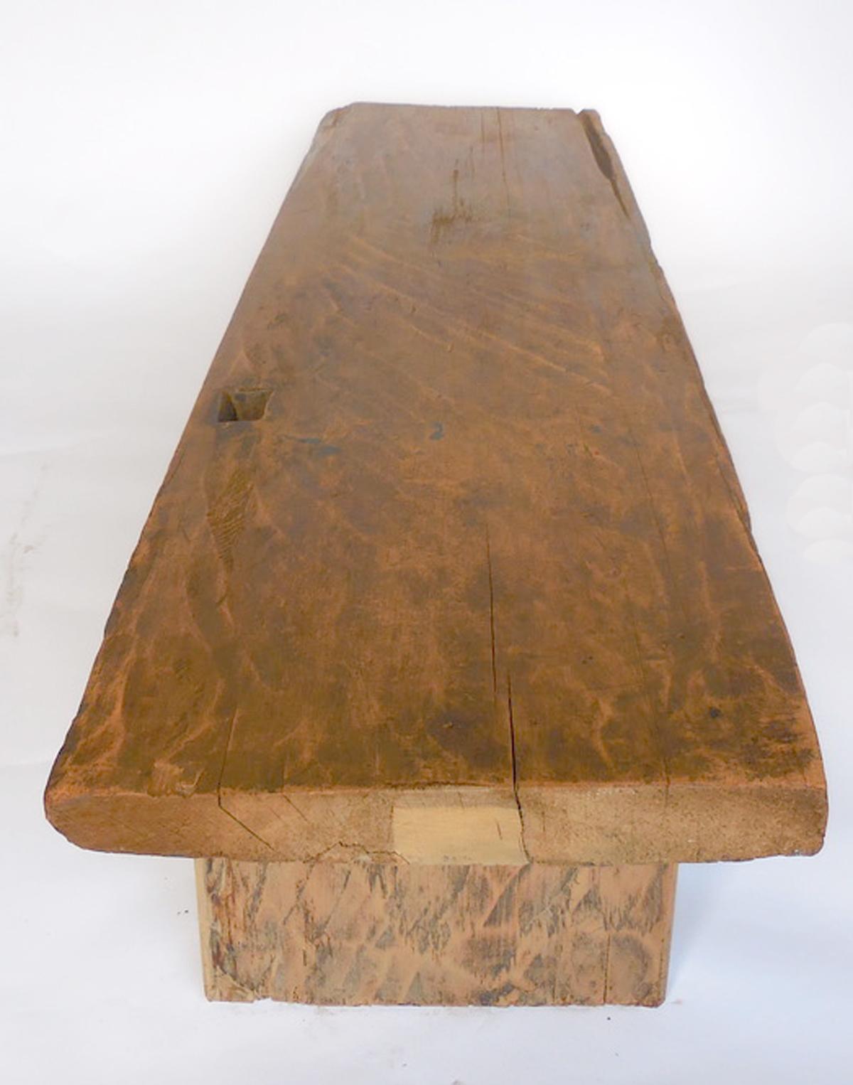 This bench or coffee table is made from an antique top that was a carpenter's bench turned door, or a door turned carpenters bench. We don't know what came first, but there are marks of hinges and also the typical rectangular hole and wear of a