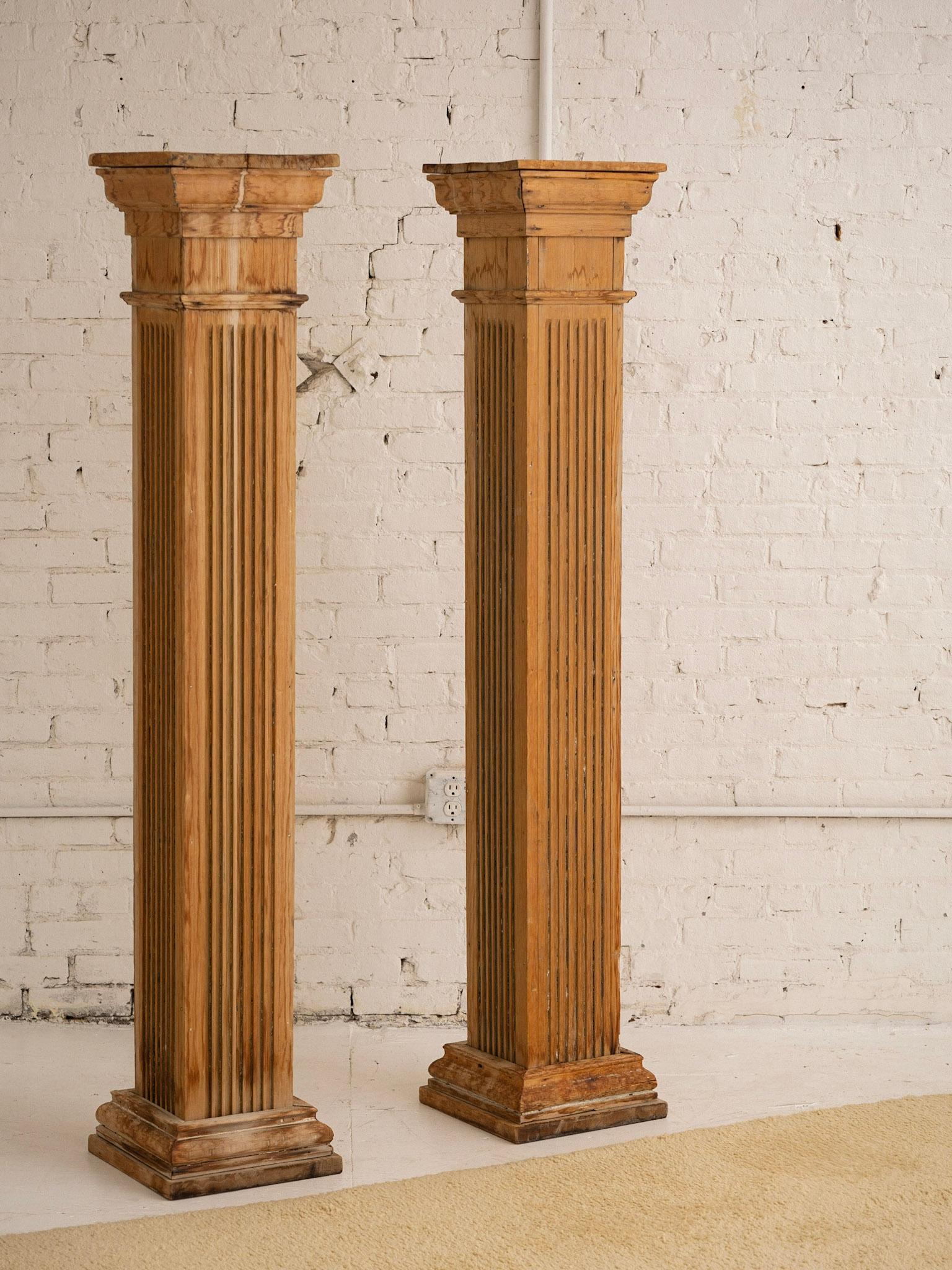 A pair of free standing antique salvaged architectural columns. Greco-Roman doric style. Square silhouette. Original paint has been removed to show a richly patinaed wood.