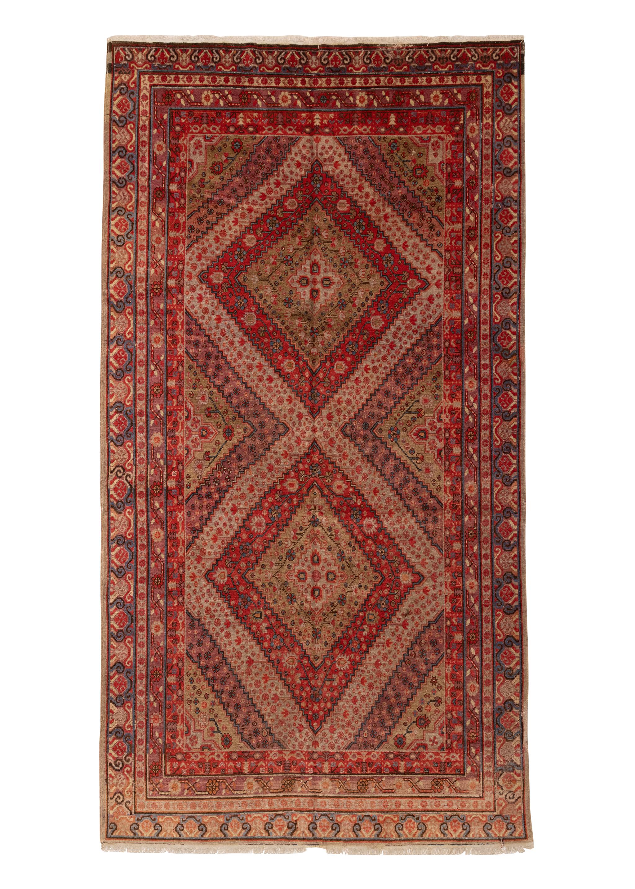 This is an antique Samarkan from East Turkistan, circa 1900s. It features diamond-like shapes inset with delicate interconnecting flowers in a palette of soft, bright colors salmon, ivory, blues reds, greens. Framing the field are multiple borders